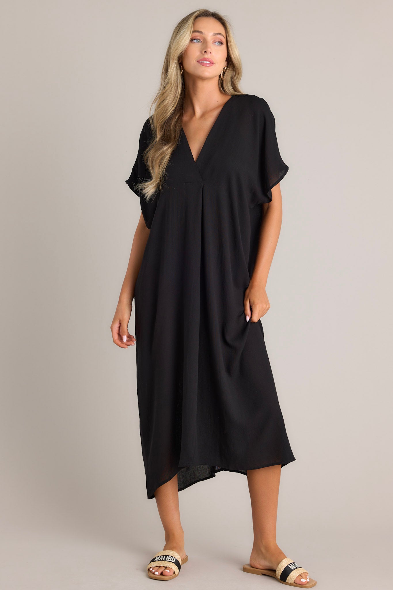 Full body view of this black cover up that features a v-neckline, short dolman sleeves, and a comfortable oversized fit.