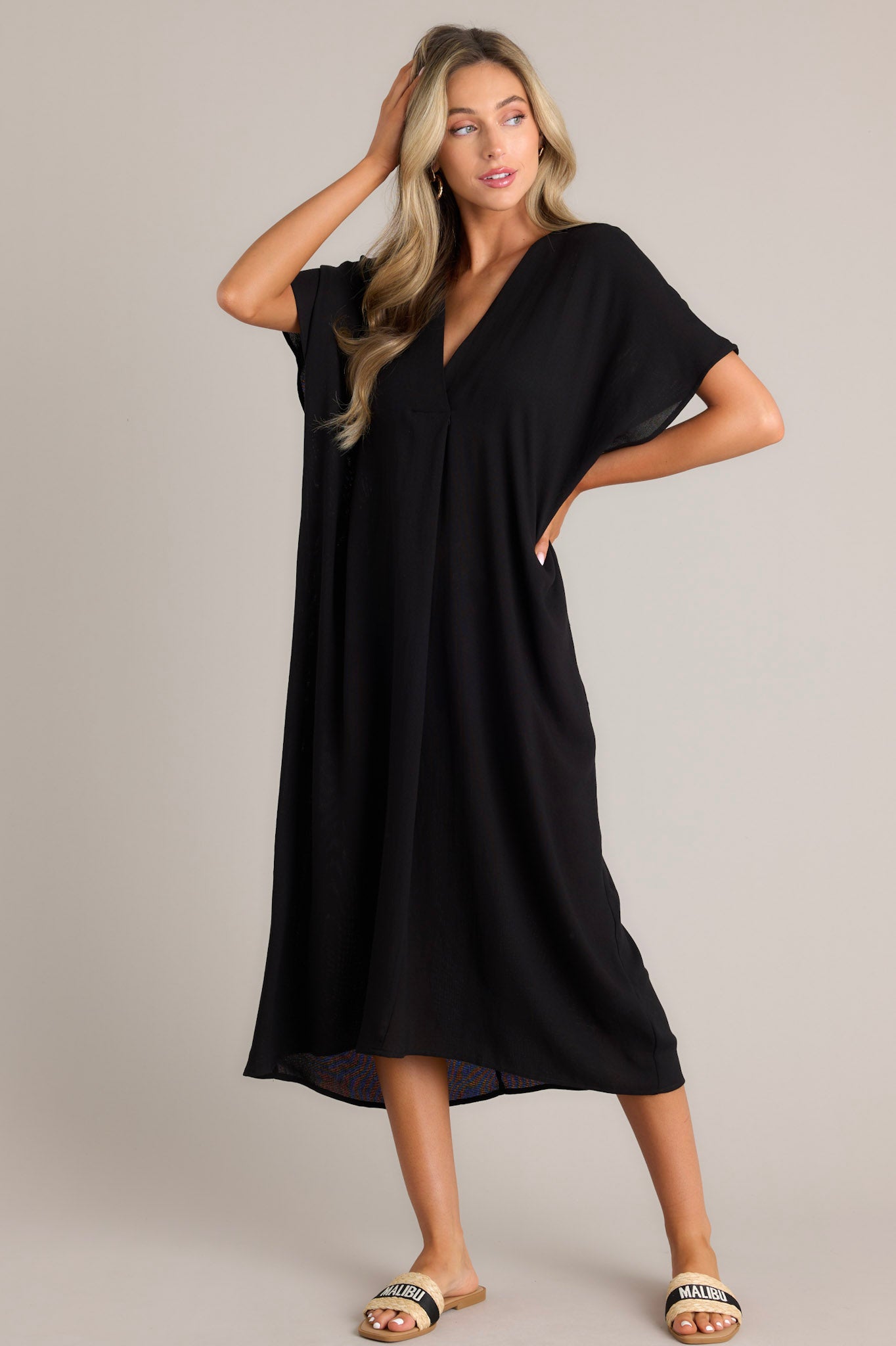 Angled full body view of this black cover up that features a v-neckline, short dolman sleeves, and a comfortable oversized fit.