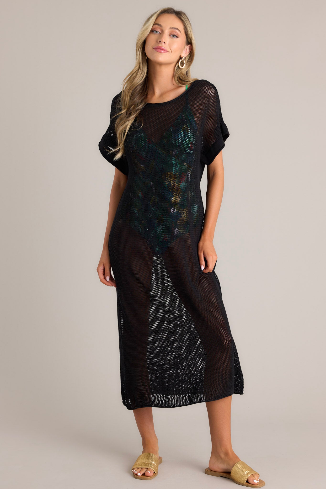 Full body  view of this black cover-up dress that features a wide rounded neckline, open back feature, an open-knit design, and cuffed short sleeves.