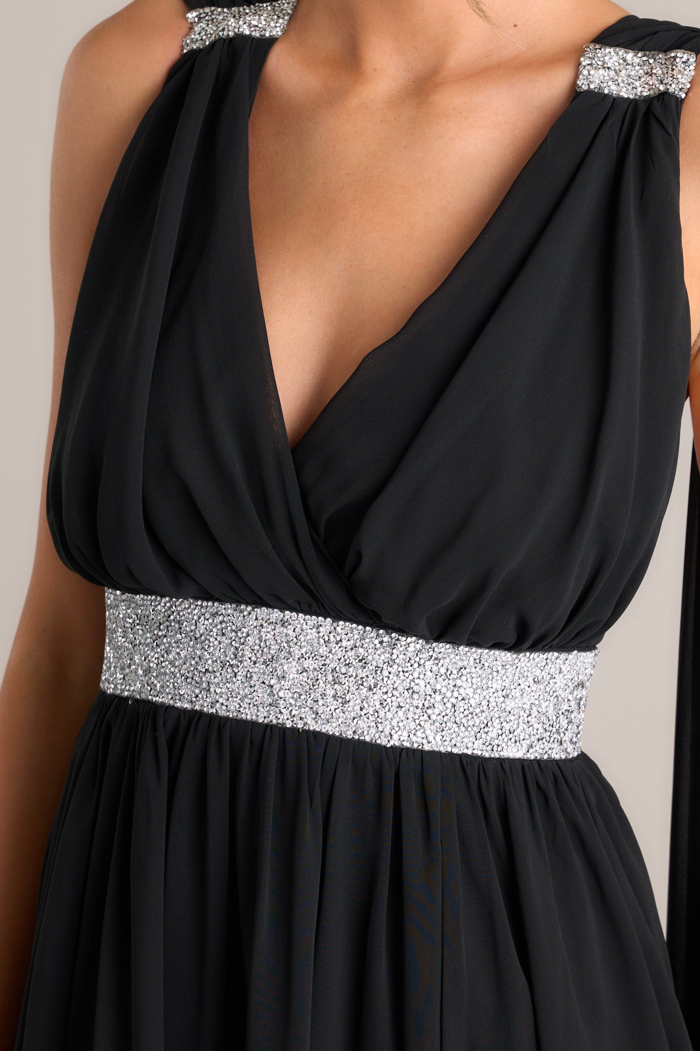 Close up of this dress that features a v-neckline and silver rhinestone detailing around collarbone area and waistline.