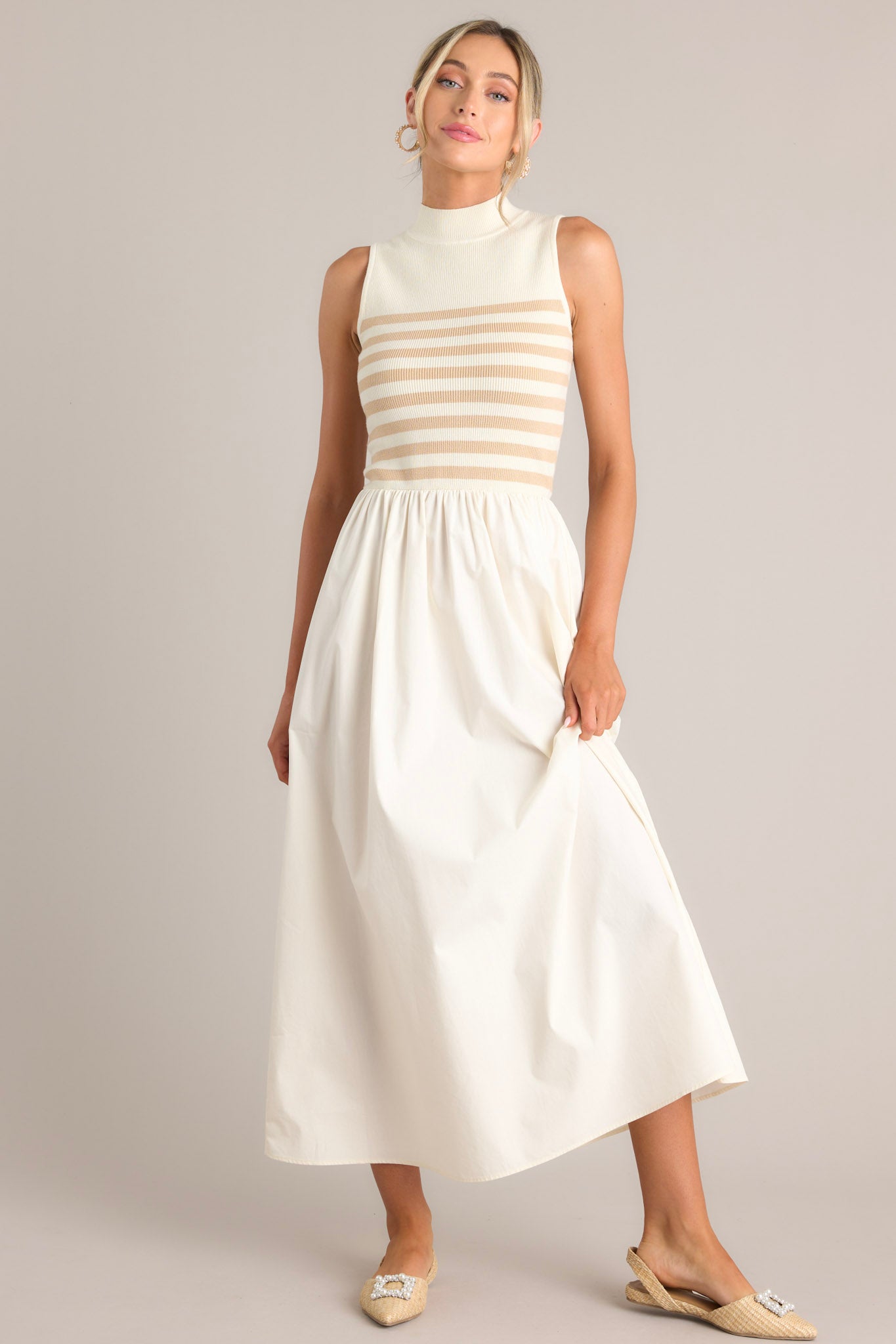 This tan and white dress features a high neckline, a striped sweater bodice, and a flowy skirt.