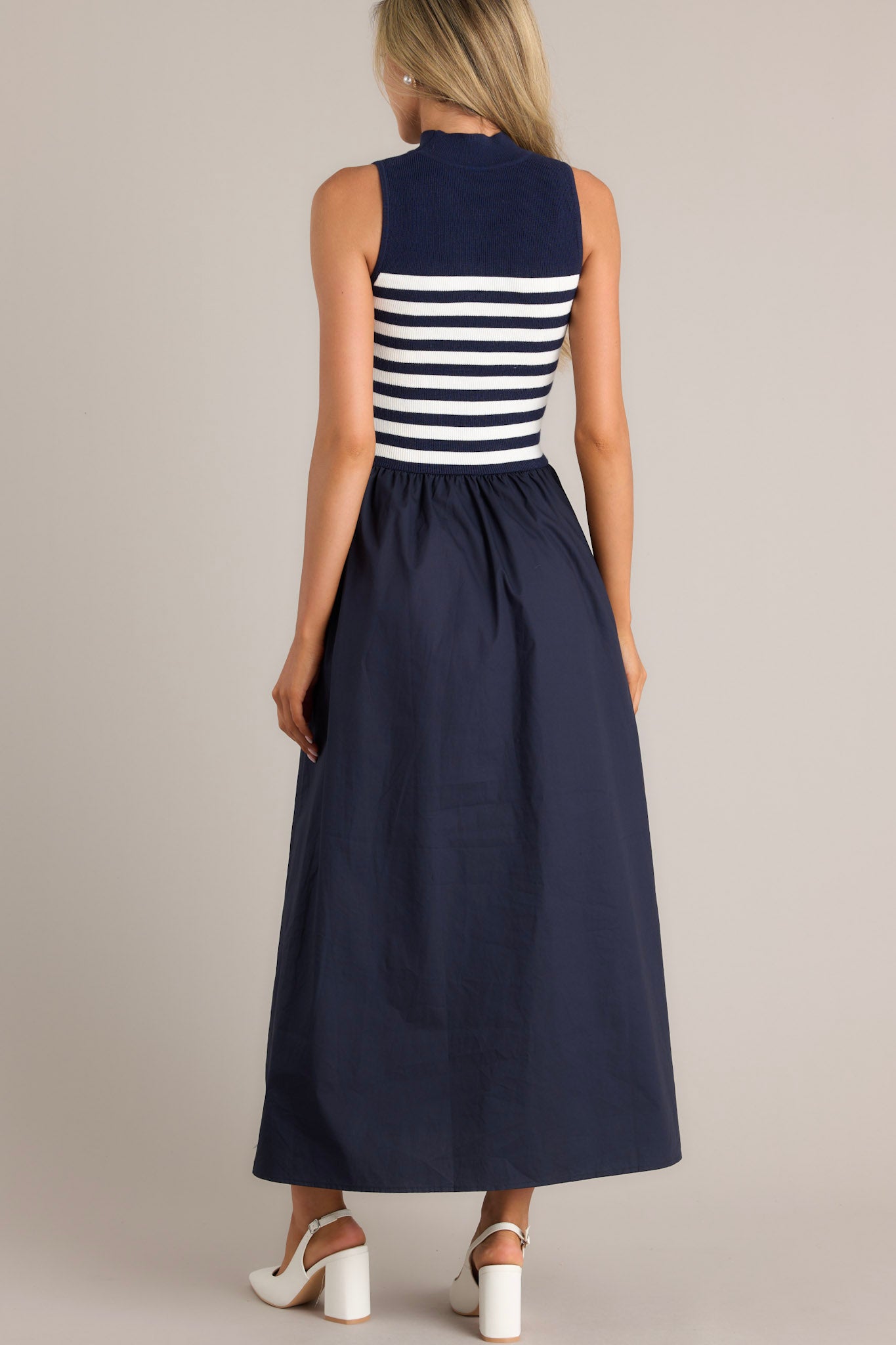 Back view of this Navy dress featuring a sleeveless striped top and a solid full-length skirt.