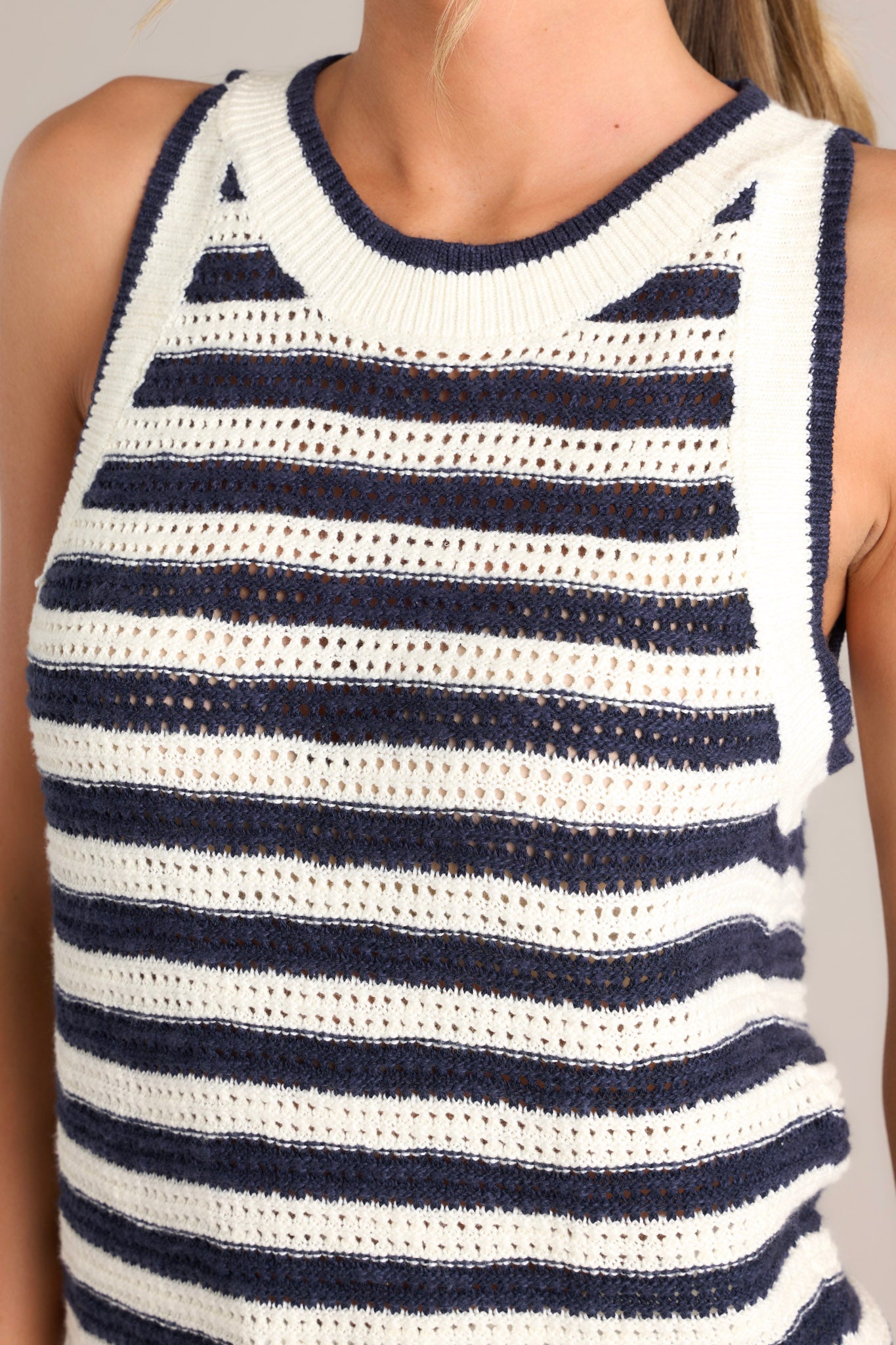 Close up view of this navy stripe tank that features a high ribbed neckline, an open knit design, and a ribbed hemline.