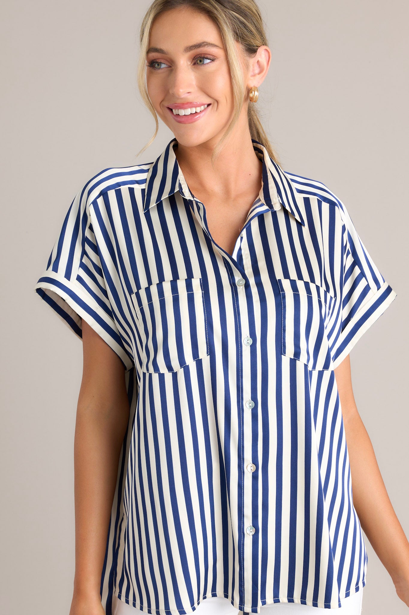 Front view of this top that features a collared neckline, a full button front, functional breast pockets, a satin-like material, wide cuffed sleeves, and a split hemline.