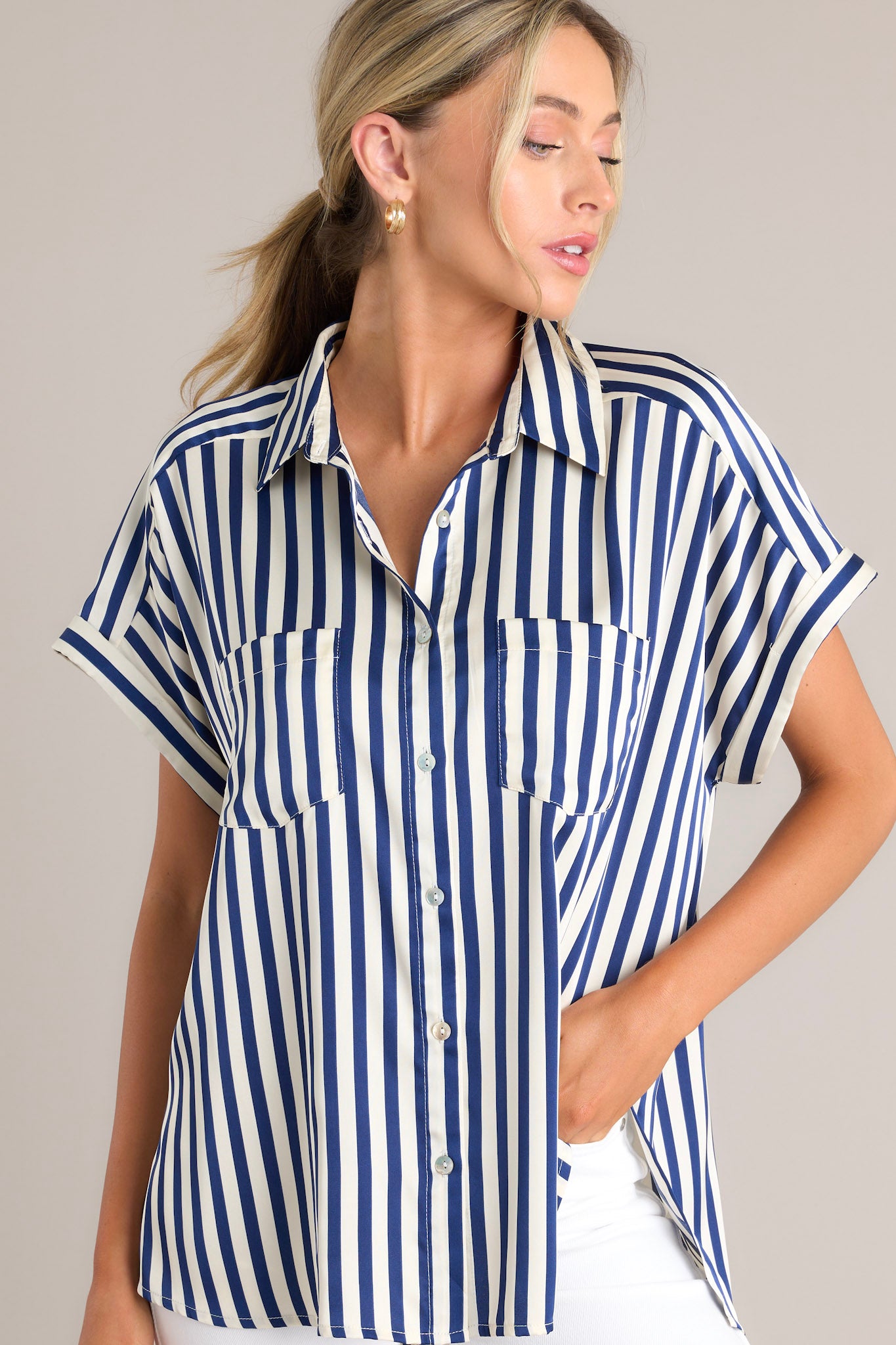 Front view of this top that features a collared neckline, a full button front, functional breast pockets, a satin-like material, wide cuffed sleeves, and a split hemline.