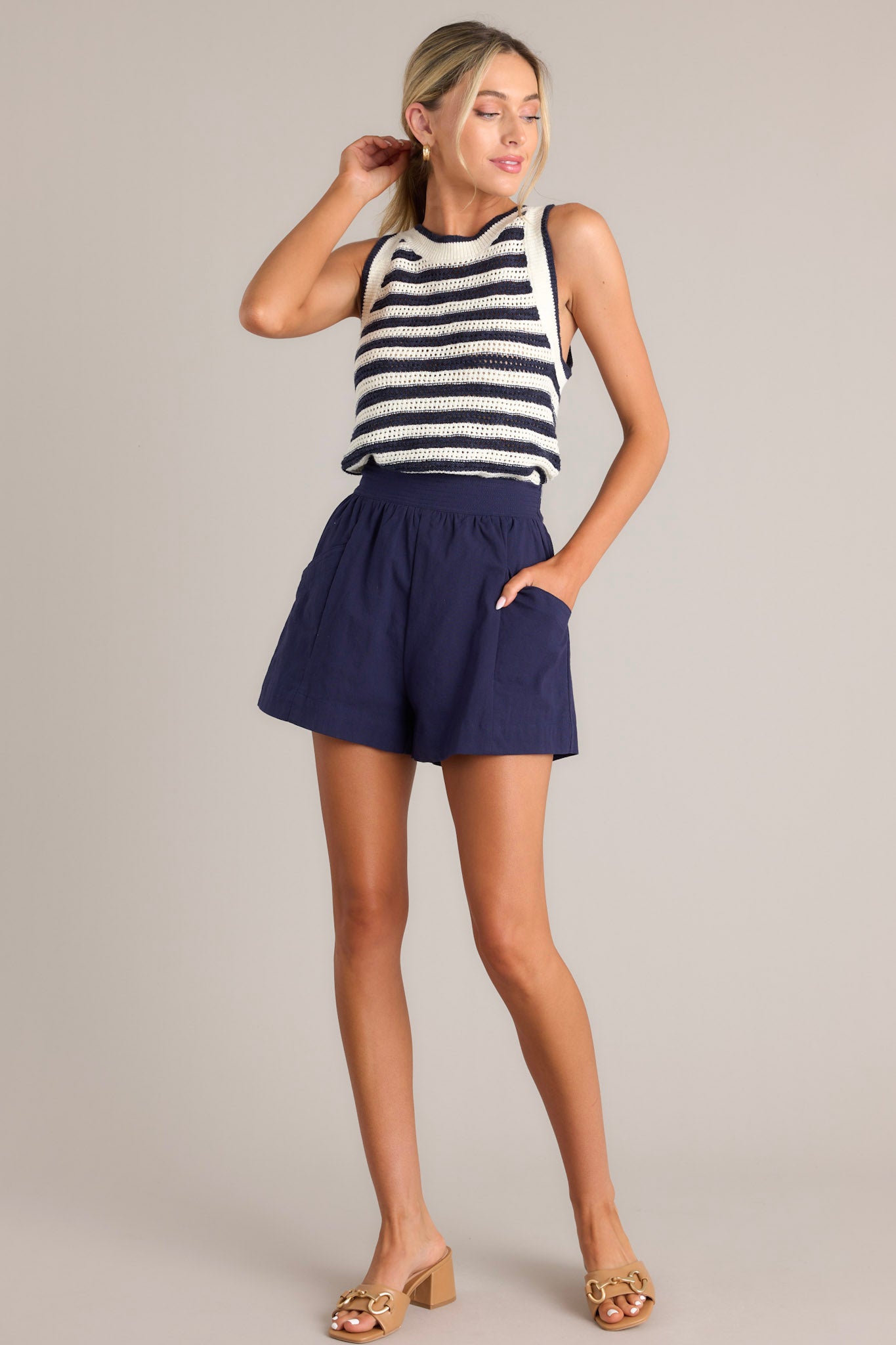 Full body view of this navy stripe tank that features a high ribbed neckline, an open knit design, and a ribbed hemline.