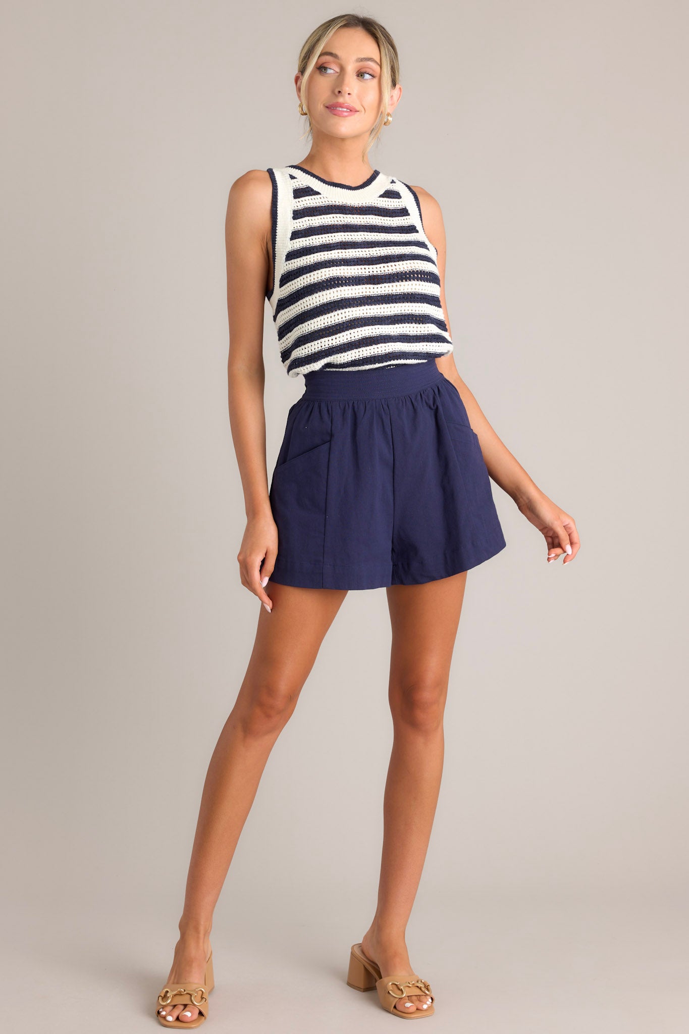 Angled full body view of this navy stripe tank that features a high ribbed neckline, an open knit design, and a ribbed hemline.