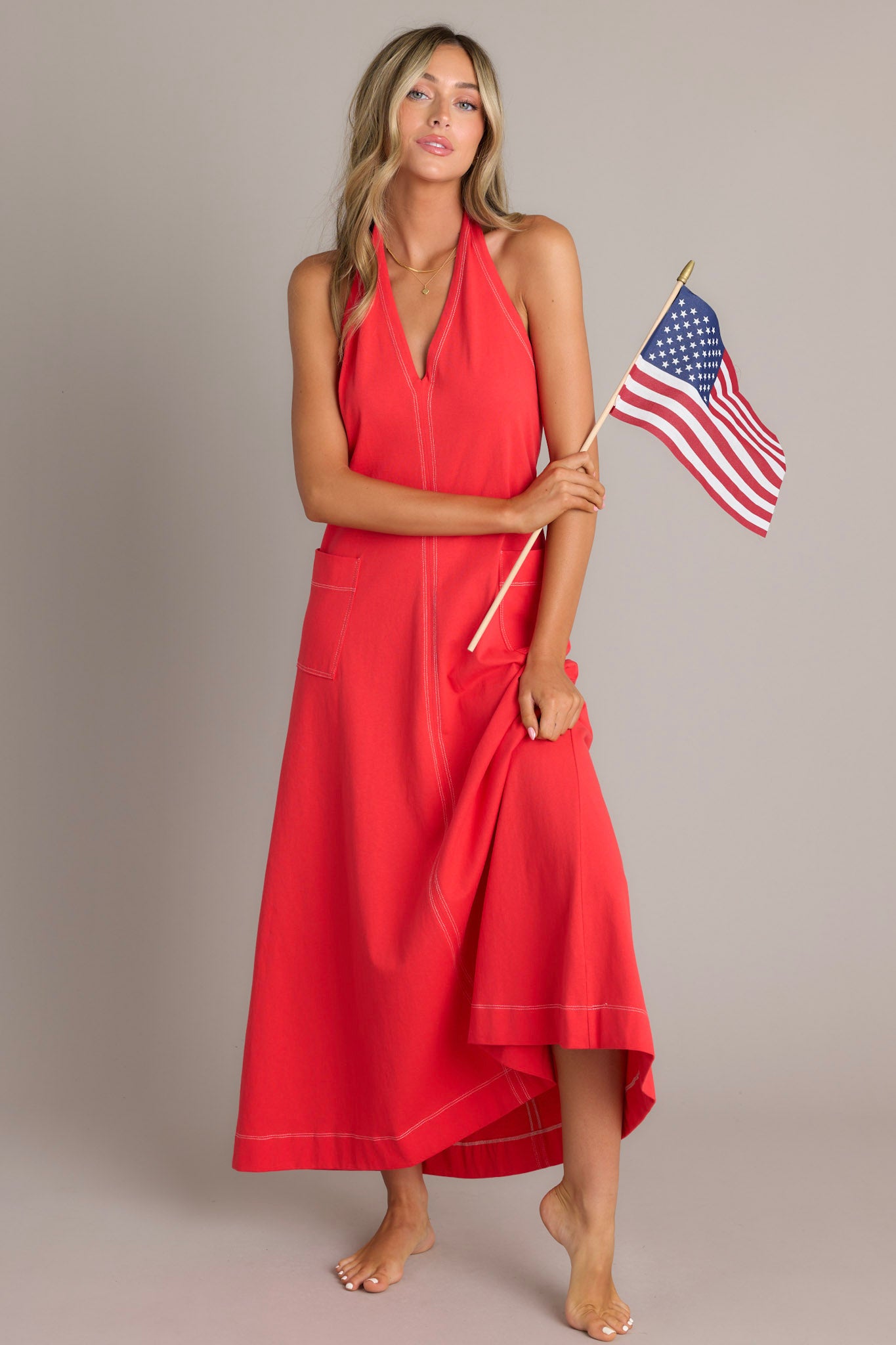 Halter-style red maxi dress featuring a deep V-neck and two front pockets.