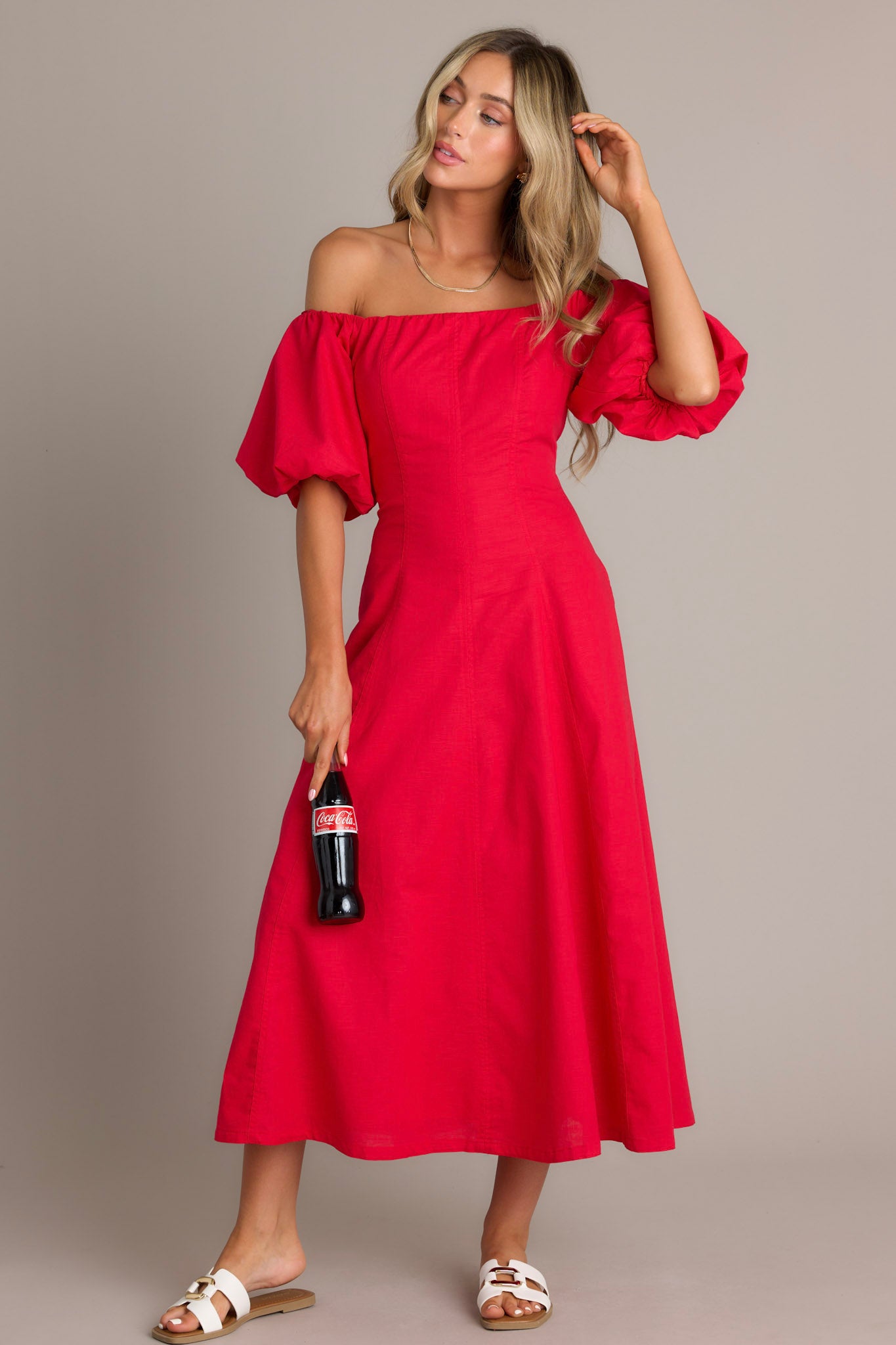 Off-the-shoulder red dress featuring puffed sleeves and a fitted bodice that flares out into a flowy, ankle-length skirt.