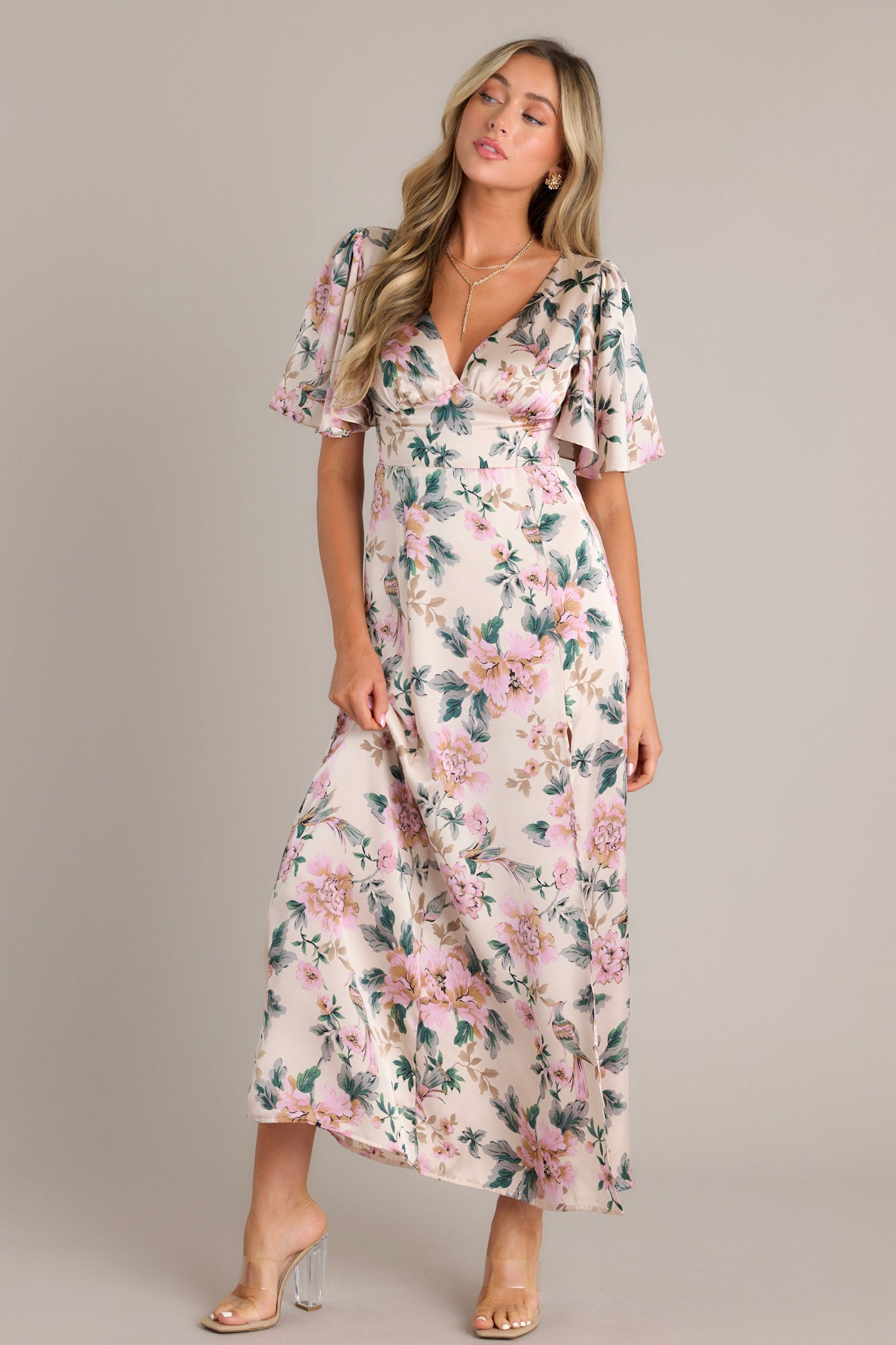 Ivory floral maxi dress with a deep V-neckline, flutter sleeves, warm floral print, fitted waist, A-line skirt, and a front slit.