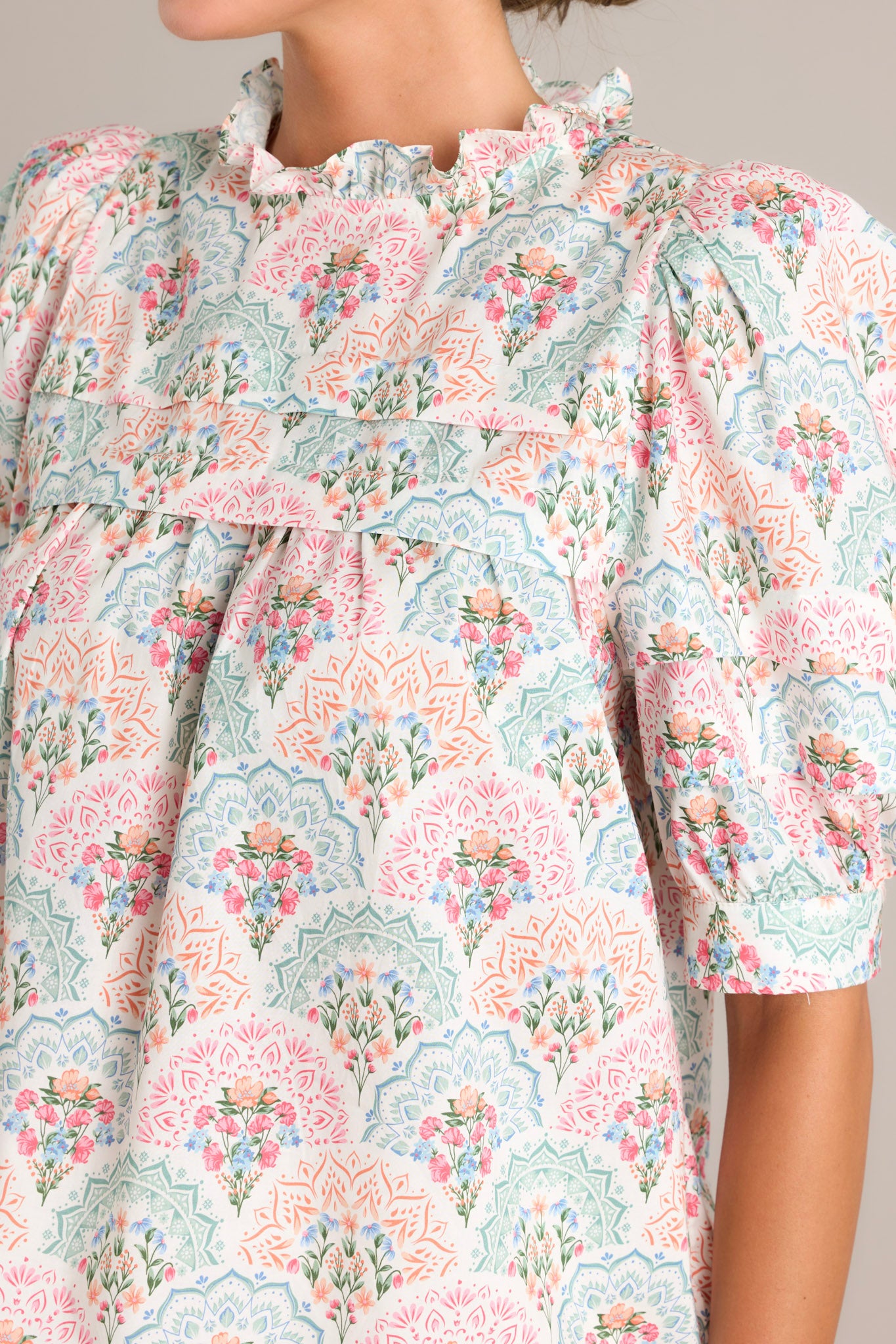 Close-up of the fabric of the pastel floral print top, highlighting the intricate floral design and ruffled yoke details.