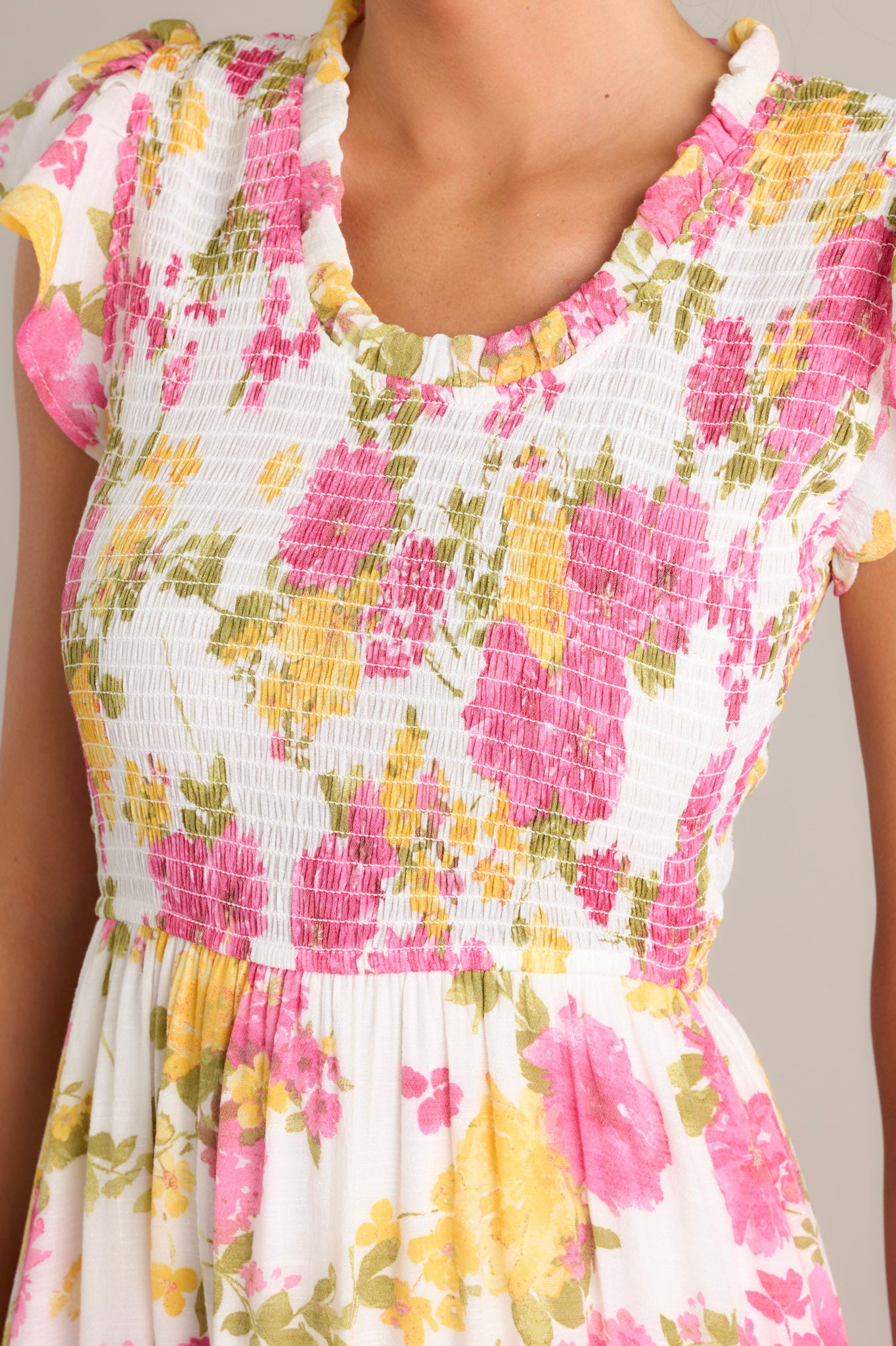 Close-up of a white and pink floral midi dress, highlighting the ruffled scoop neckline and smocked bodice.