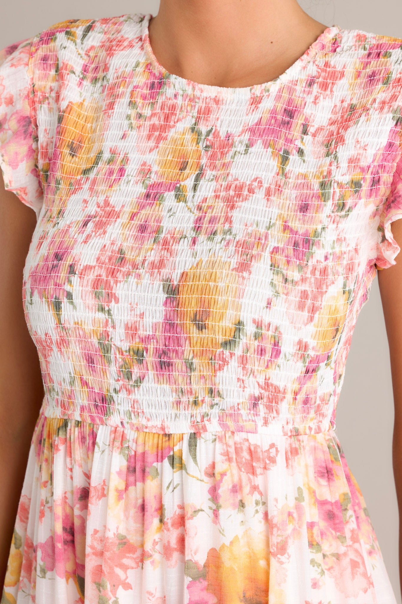 Fabric detail of this pink floral midi dress, highlighting the colorful floral pattern and smocked texture.