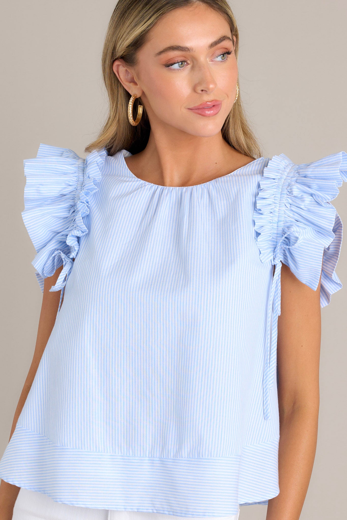 Close-up of this blue stripe top highlighting the crew neckline, vertical stripes, and layered ruffle sleeves with adjustable bows.