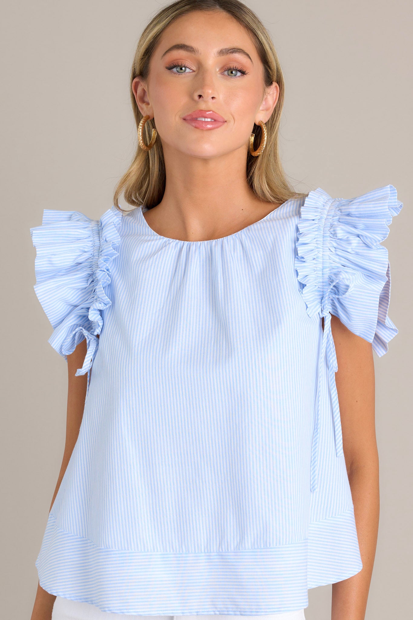 Focused view of this blue top featuring ruffle sleeves, emphasizing the adjustable bows and the vertical stripe pattern.
