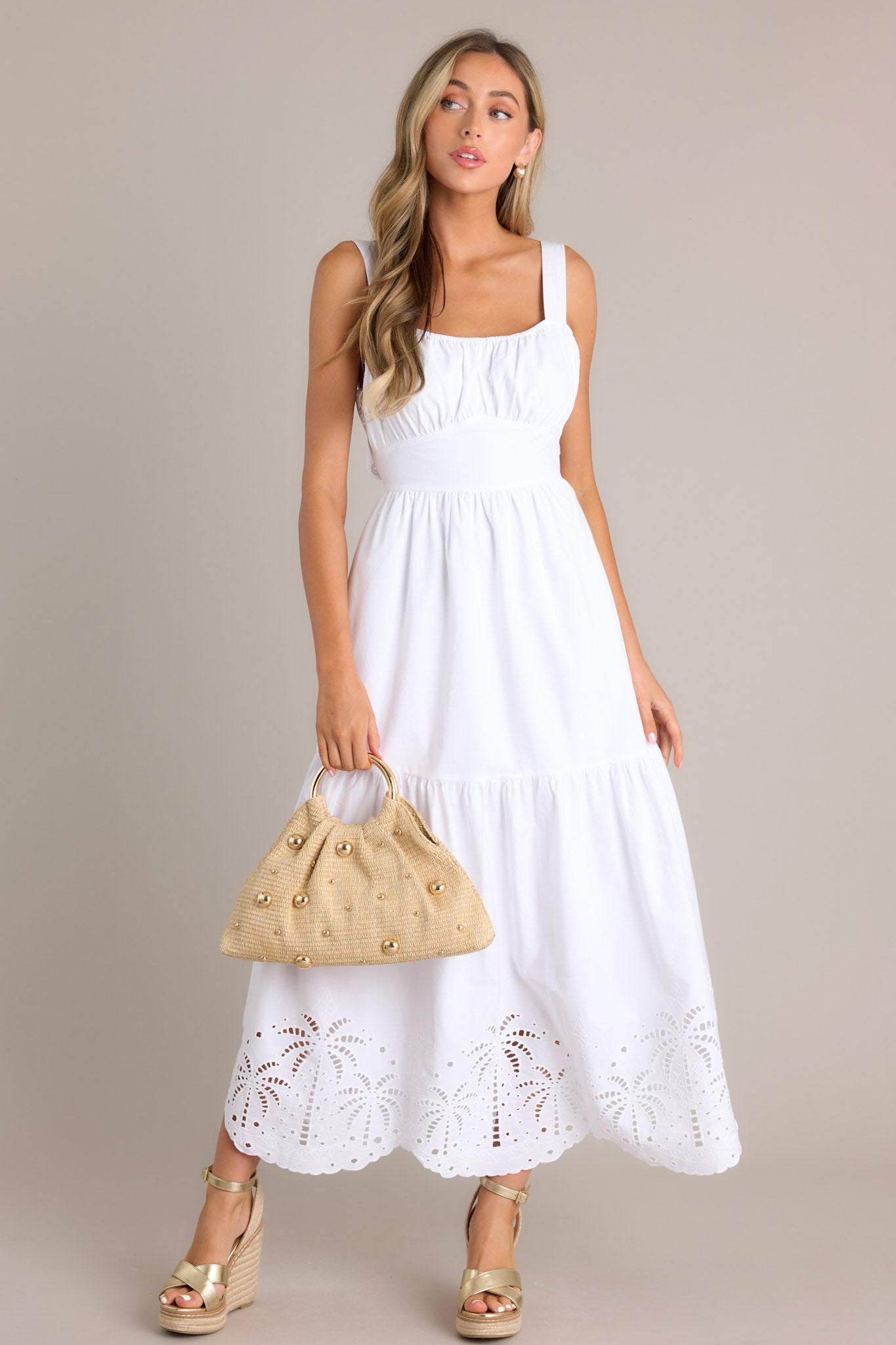 This white midi dress features an elastic square neckline, thick adjustable straps, a thick waistband with a self-tie back feature, an open lower back, a single tier, palm eyelet detailing, and a scalloped hemline.