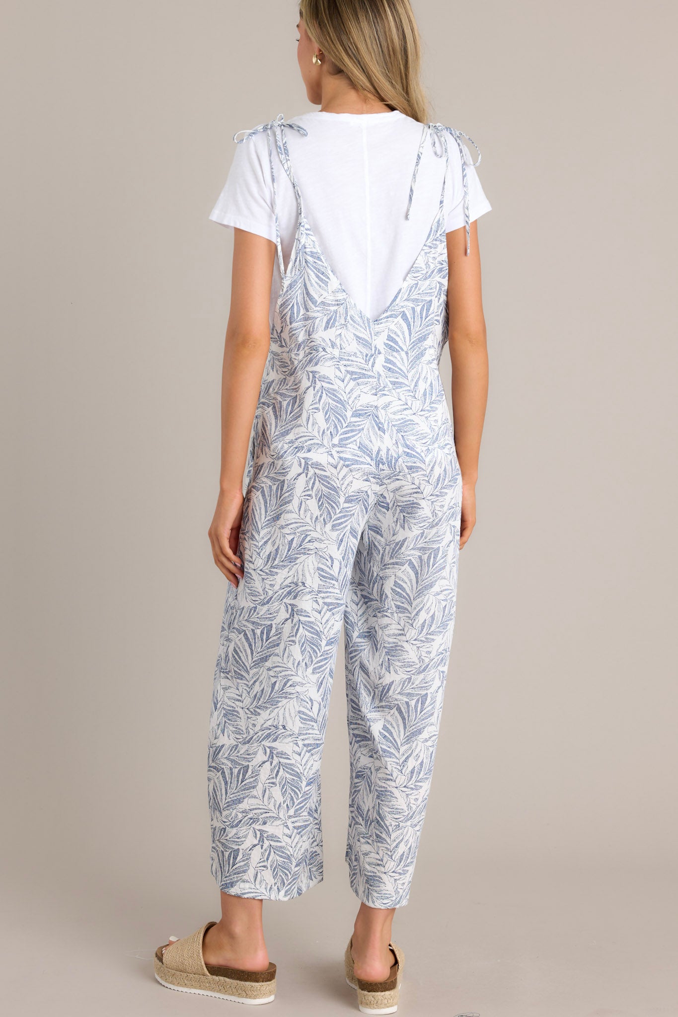 Back view of this Casual jumpsuit featuring a light blue and white leaf print, wide legs, and adjustable tie straps.