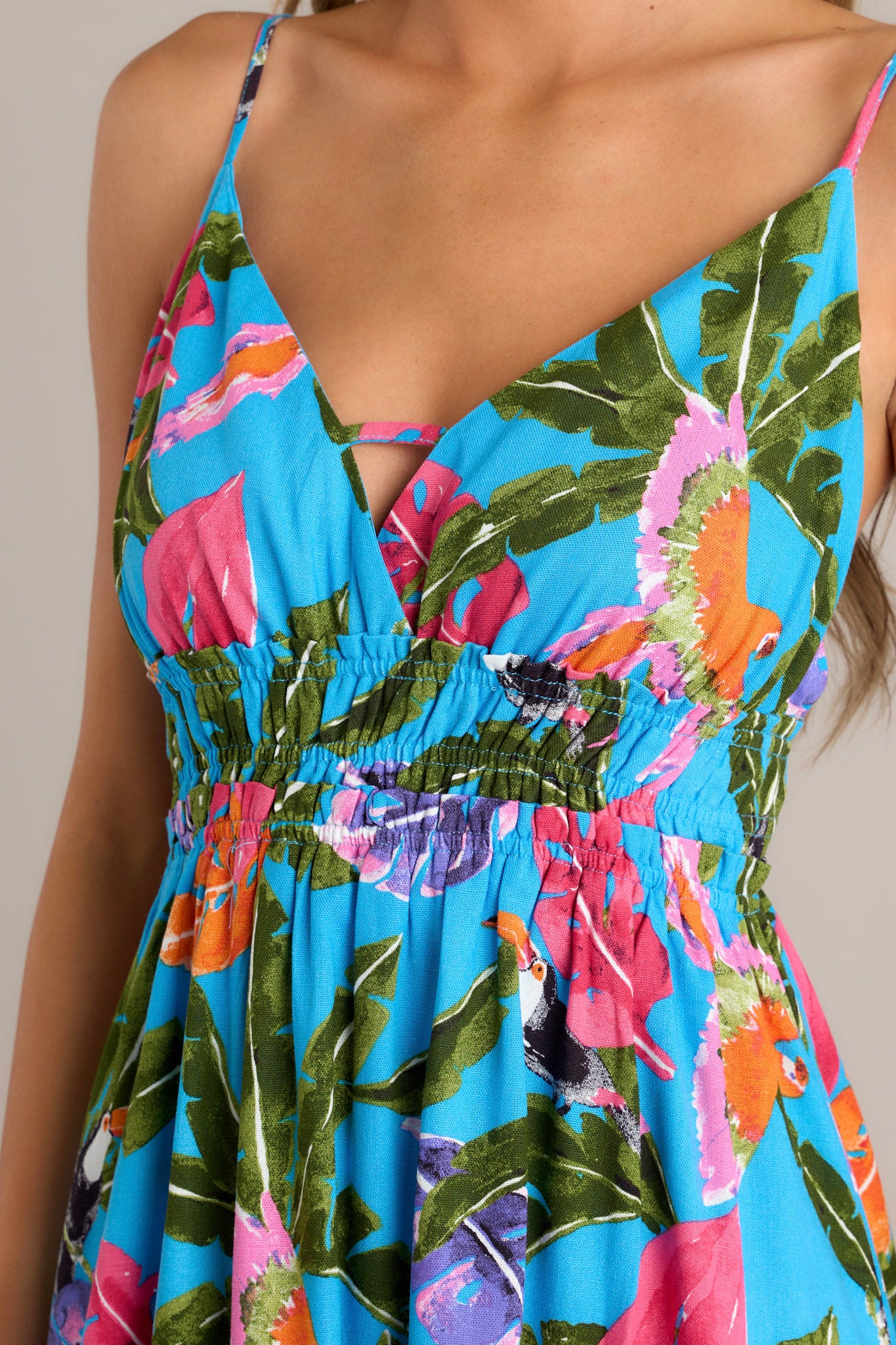 Close-up of the vibrant fabric, smocked waistband, and V-neckline on a blue midi dress with thin adjustable straps.