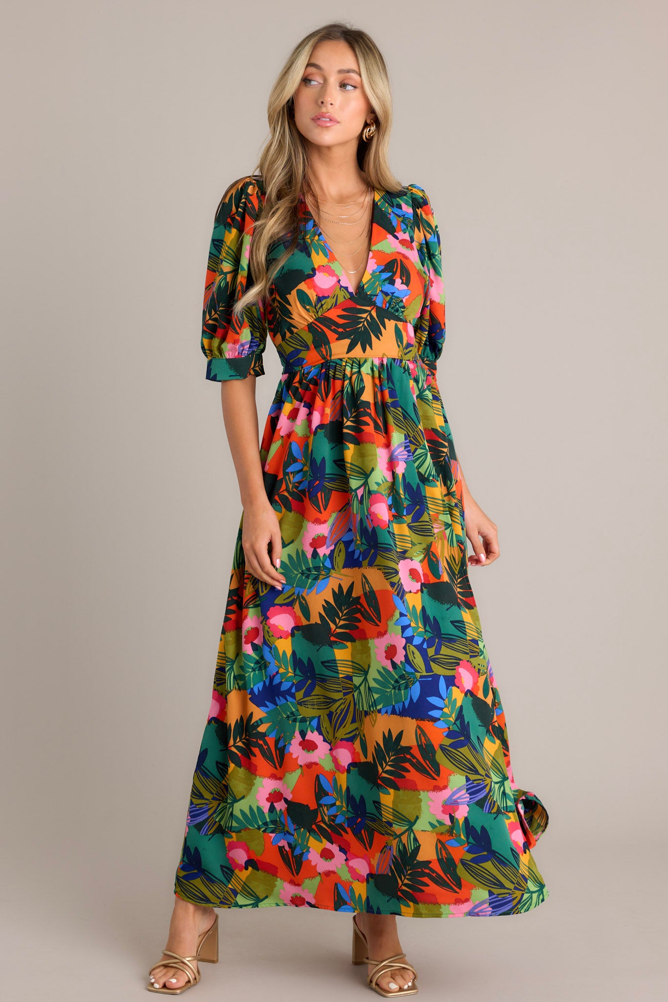 Angled view of a boldly patterned tropical dress with a flowing skirt and puff sleeves.