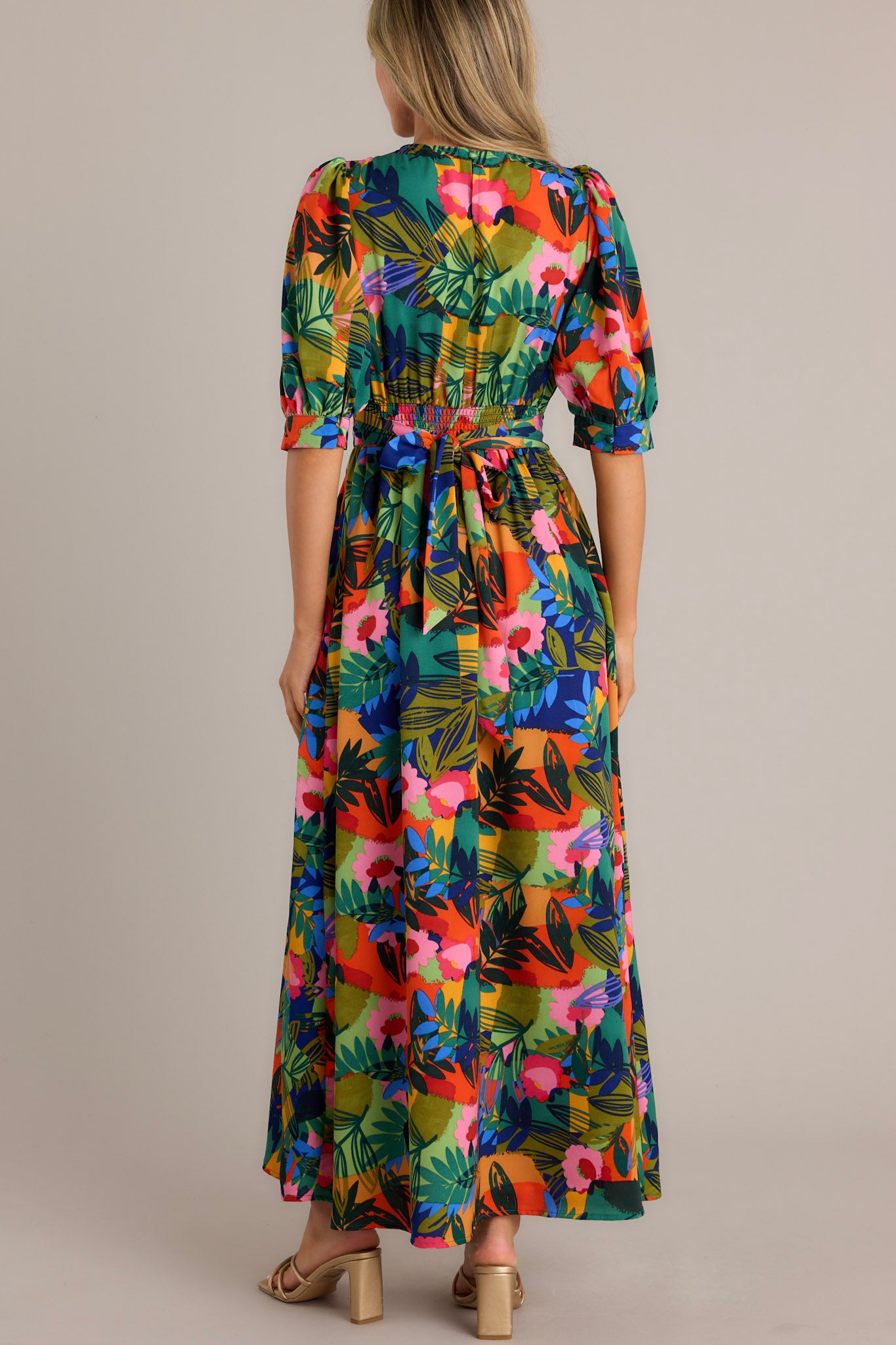 Back view of a tropical-themed long dress featuring vibrant tropical patterns and a deep V-neckline.