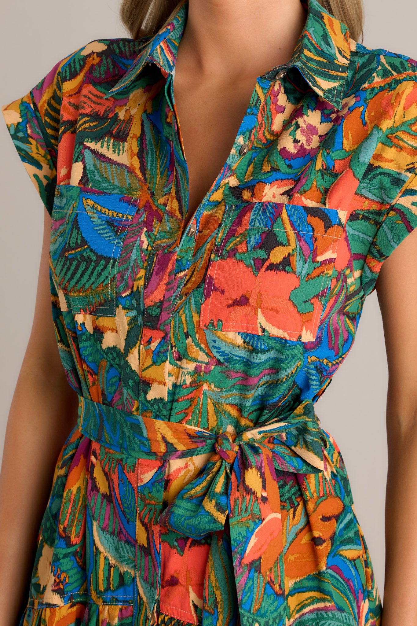 Close-up of the collared neckline, functional breast pockets, and hidden button front on a green midi dress with a self-tie belt and cuffed short sleeves.