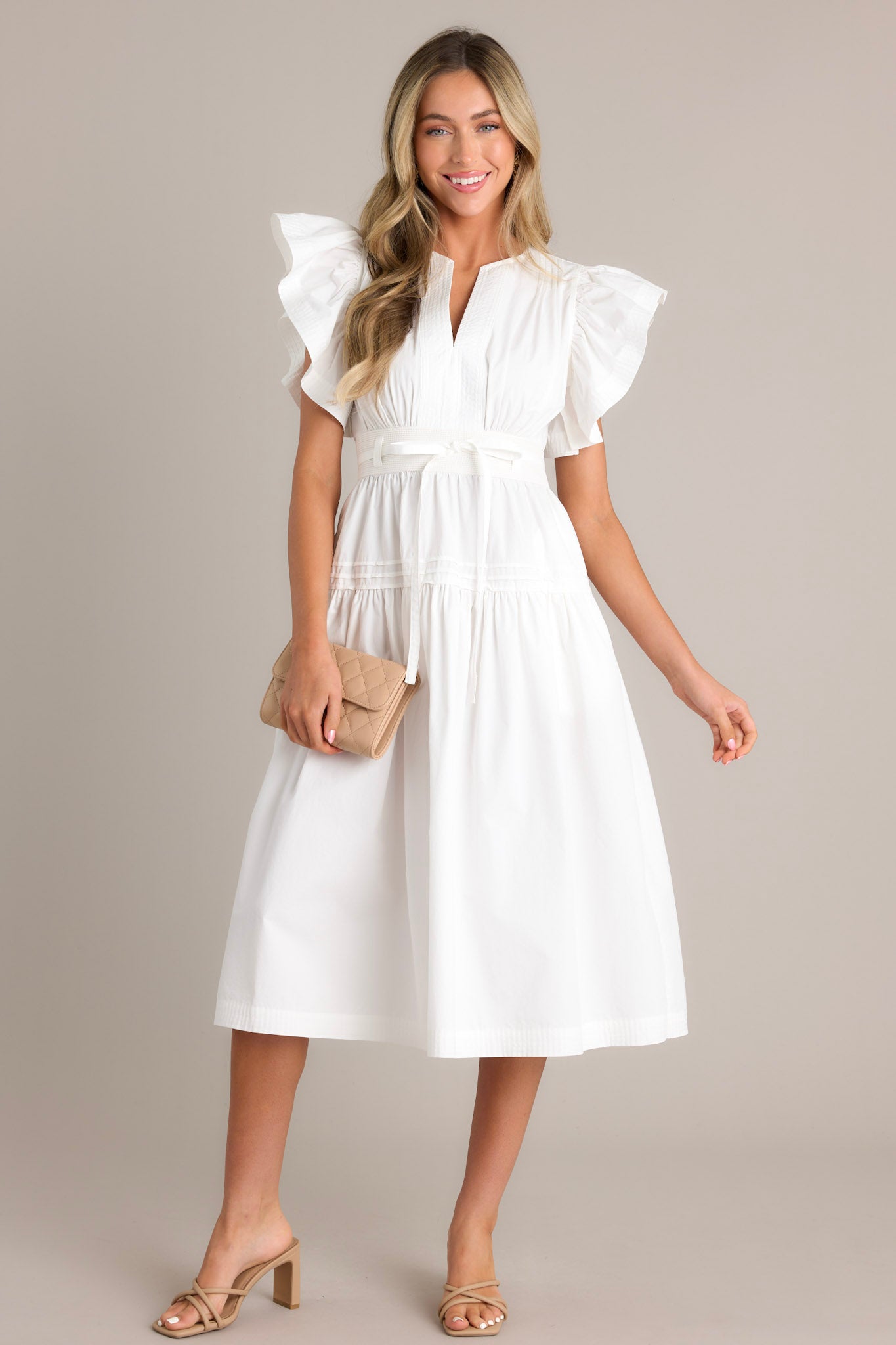 This white midi dress features a v-neckline, subtle chest pleats, a discrete side zipper, a thick waistband with a self-tie belt, a smocked waist insert, functional hip pockets, a single tier, and ruffled short sleeves.