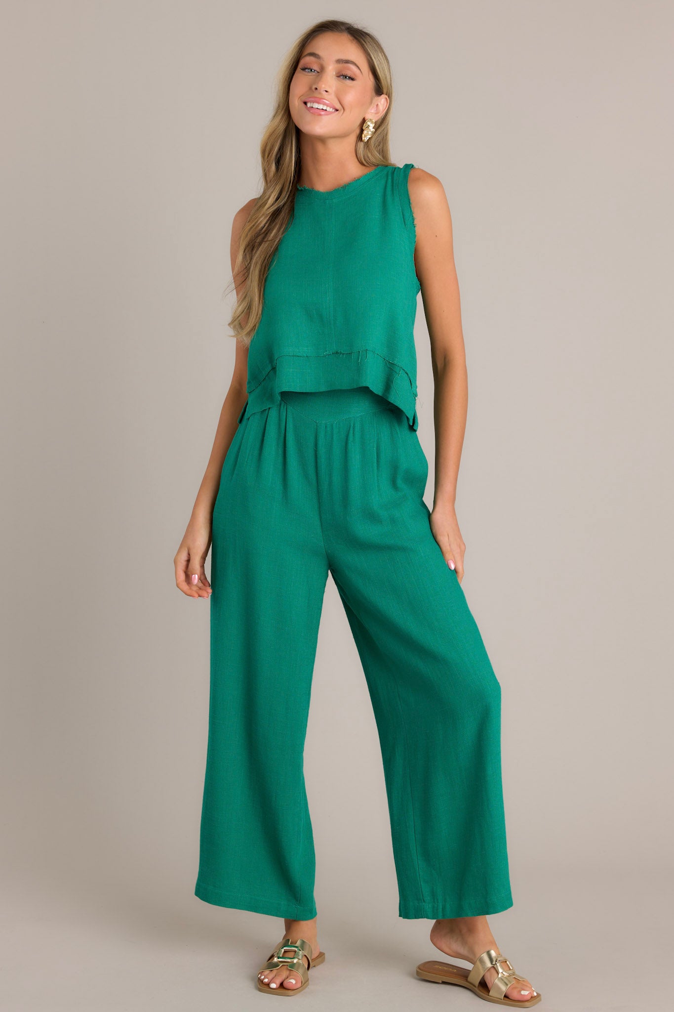 Front angled view of high-waisted green pants featuring an elastic insert in the back, functional hip pockets, lightweight fabric, and a wide leg design