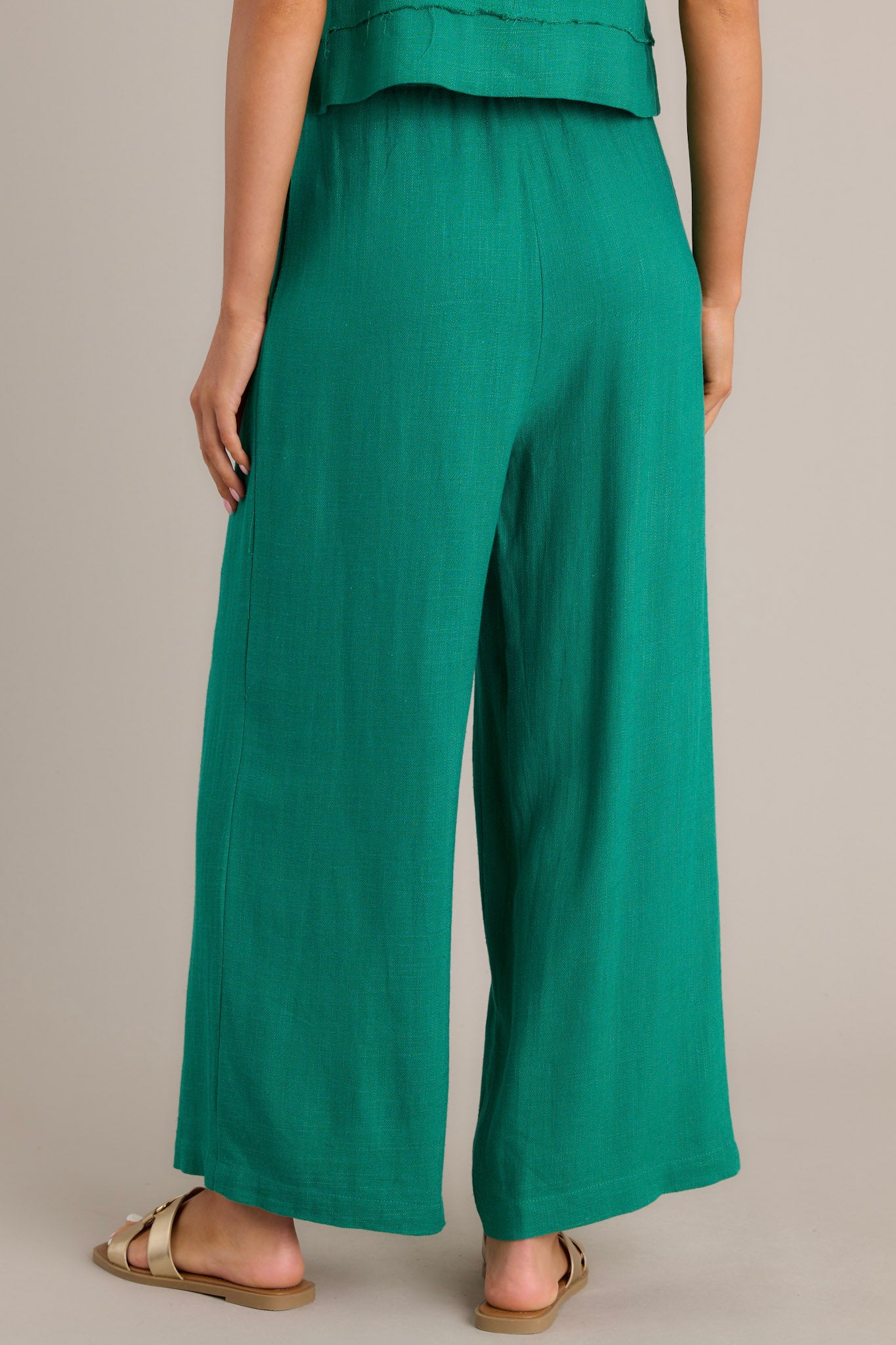 Back view of green pants showcasing the elastic insert in the back, lightweight fabric, and wide leg cut.