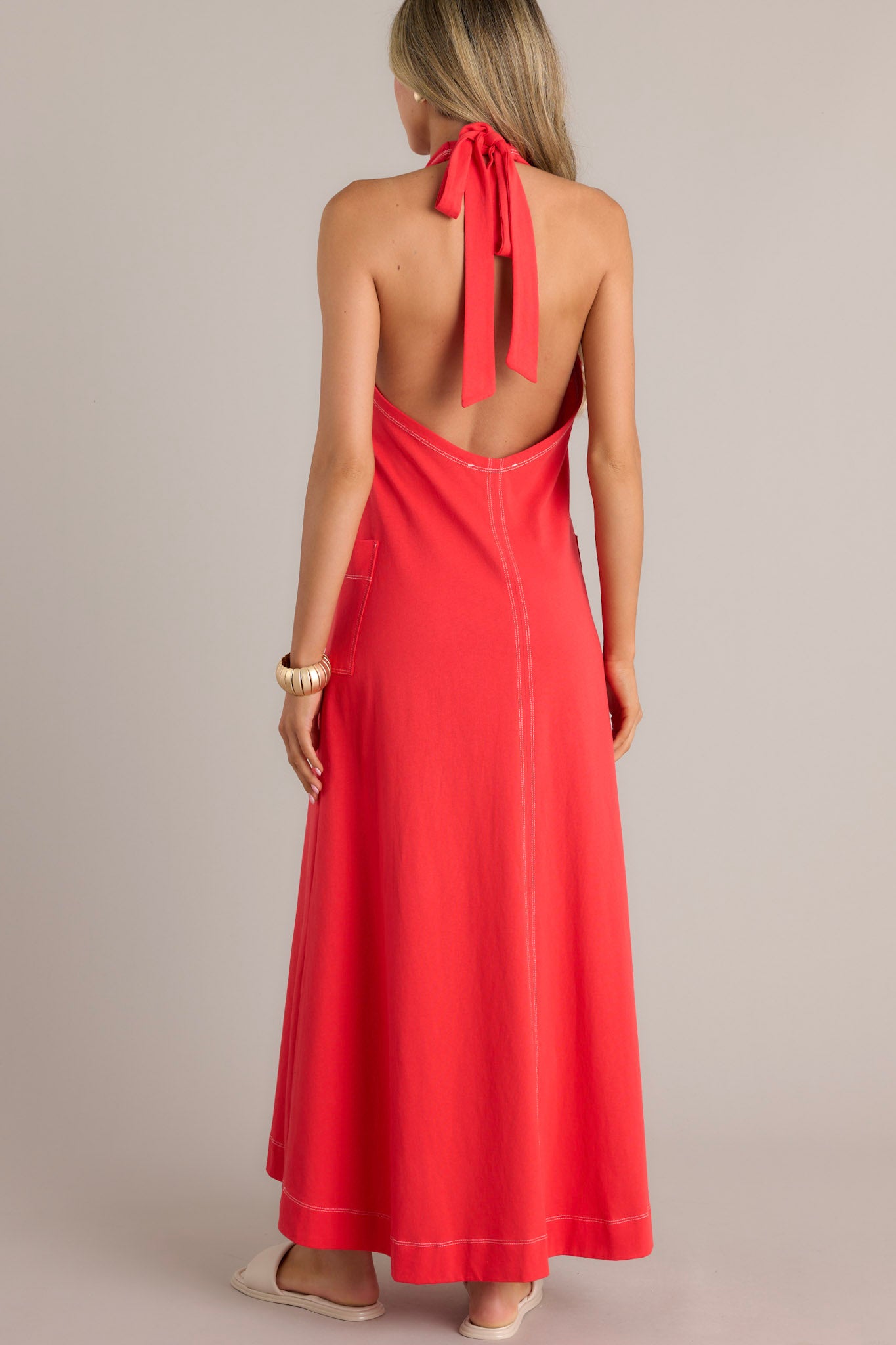 Back view of this Casual red maxi dress with contrast stitching, V-neck, and large front pockets.