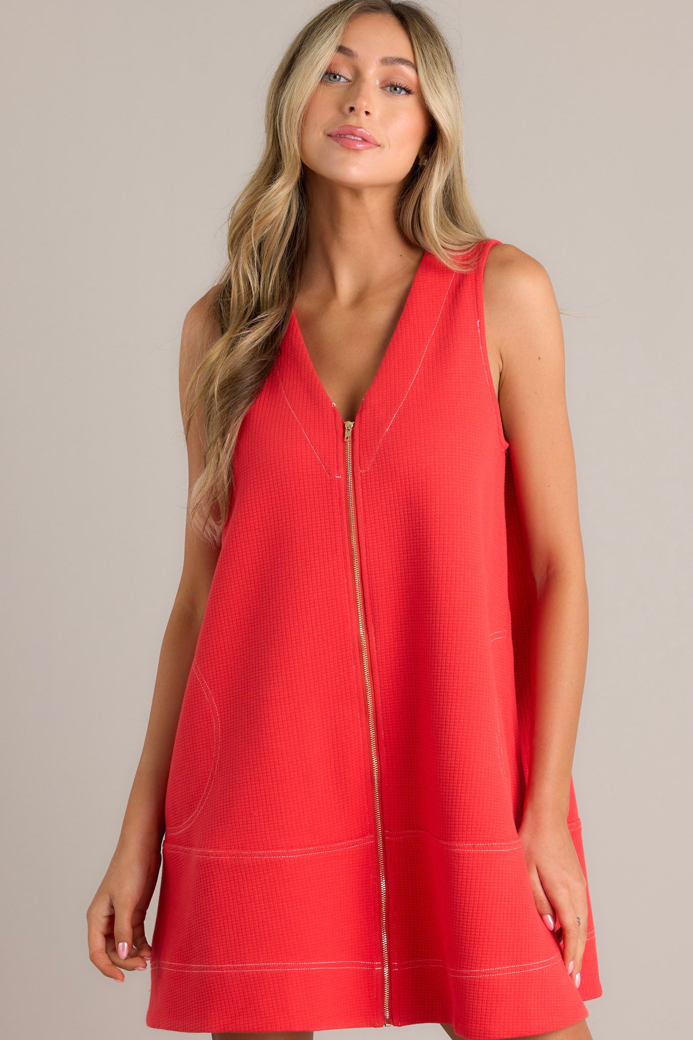 Sleeveless, A-line coral dress with a front zipper detail and two large pockets, featuring a loose and casual fit.