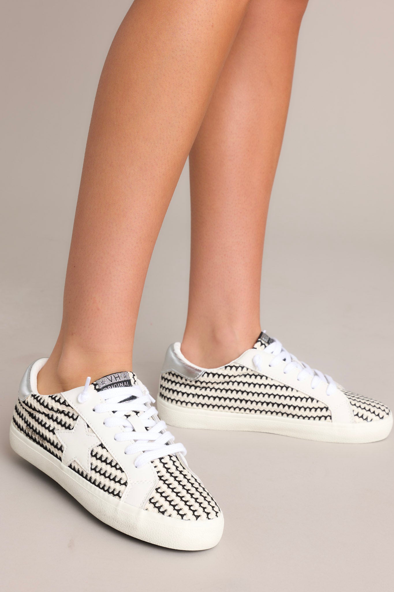 Angled front view of these black and white shoes that feature a rounded toe, no-tie laces, replacement laces, star detailing , and a thick sole.