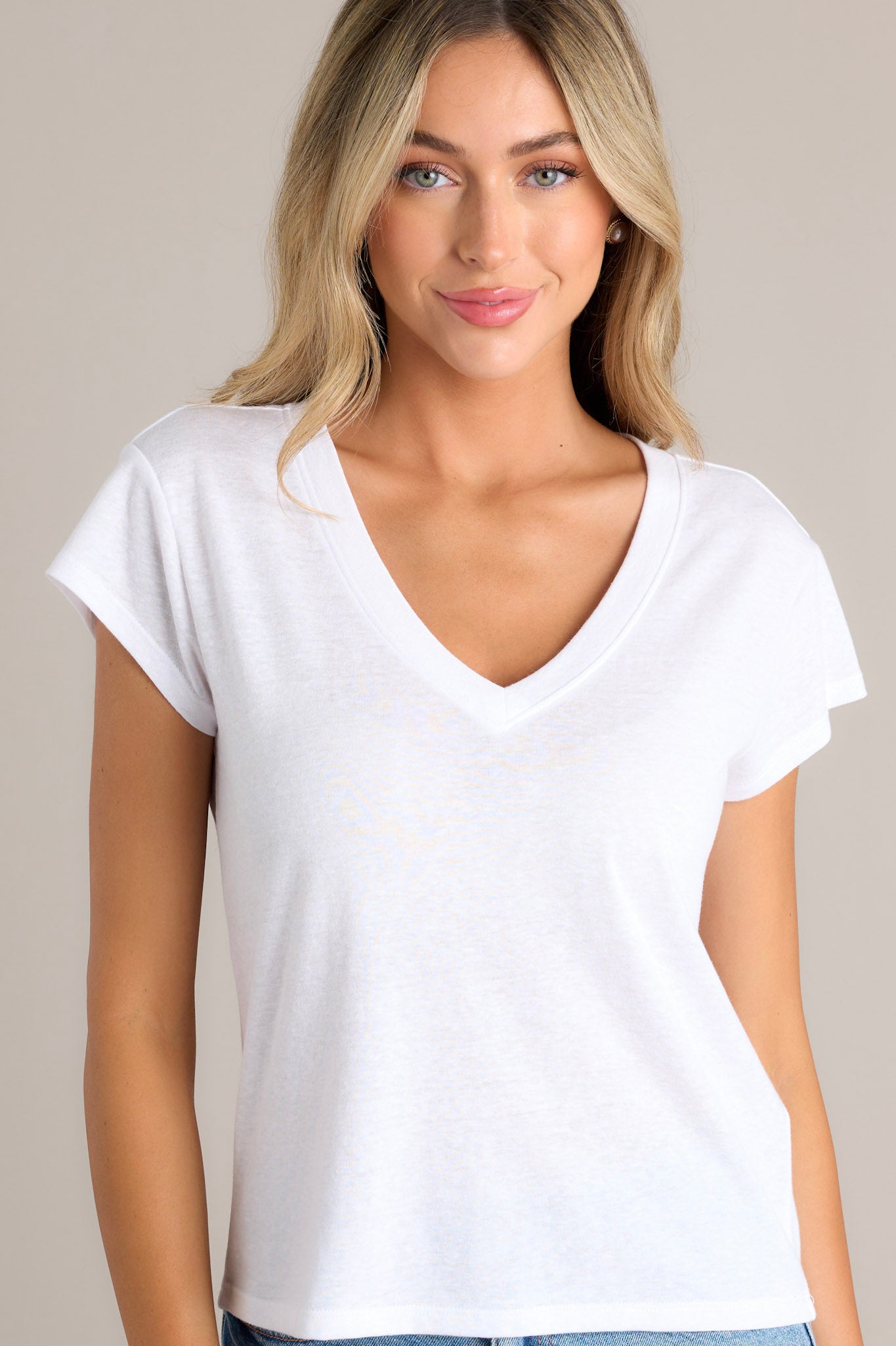 Angled view of the neckline of this white tee that features a v-neckline, a soft & lightweight fabric, a versatile design, and loose short sleeves.