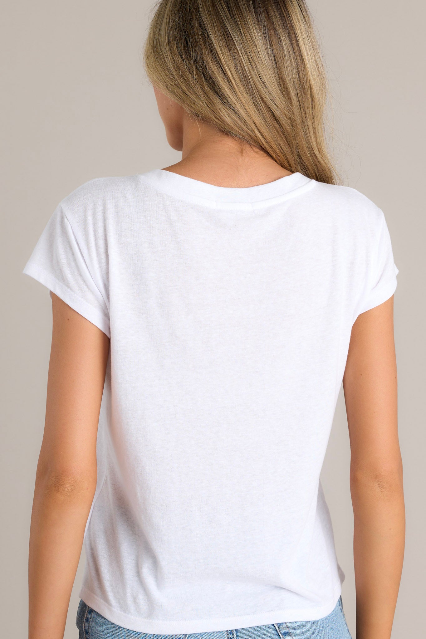 Back view of the neckline of this white tee that features a v-neckline, a soft & lightweight fabric, a versatile design, and loose short sleeves.