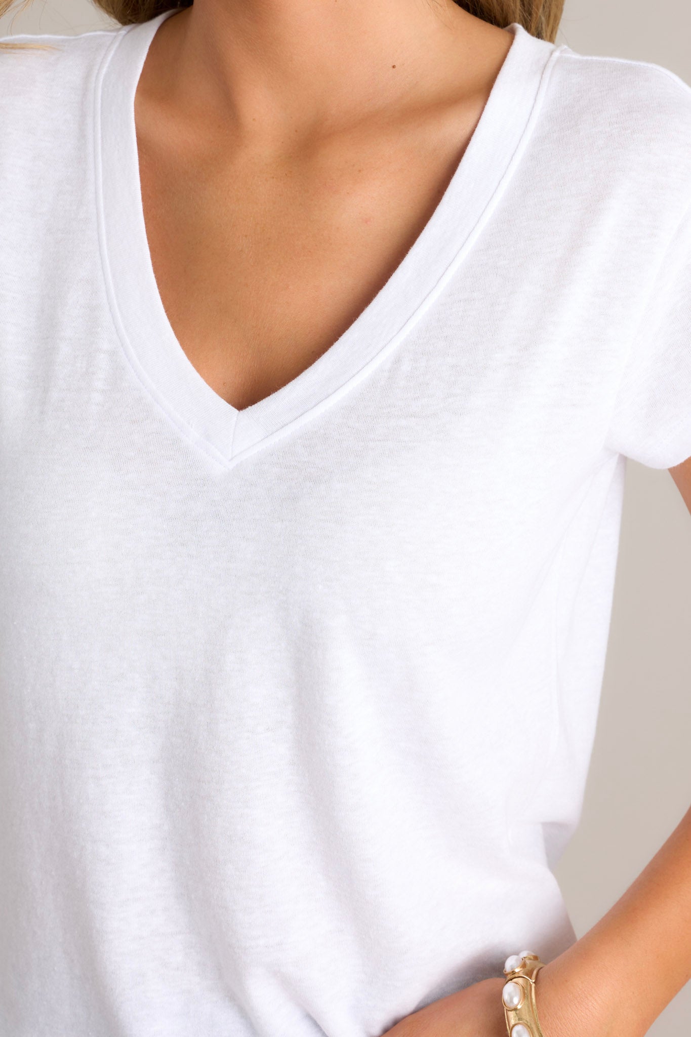 Close up view of the neckline of this white tee that features a v-neckline, a soft & lightweight fabric, a versatile design, and loose short sleeves.