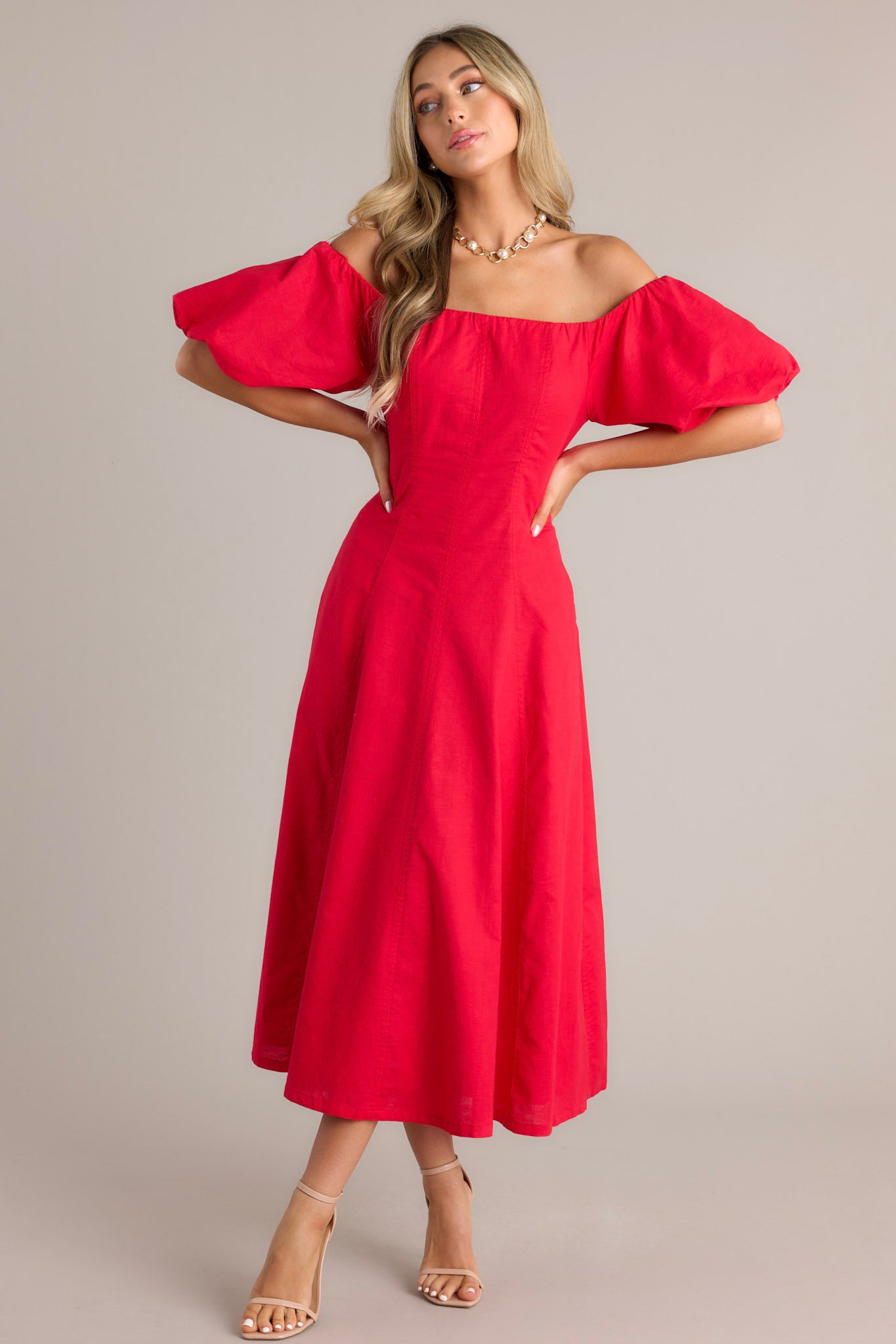 Off-the-shoulder red dress with puffed sleeves, a fitted bodice, and a flowy, ankle-length skirt.