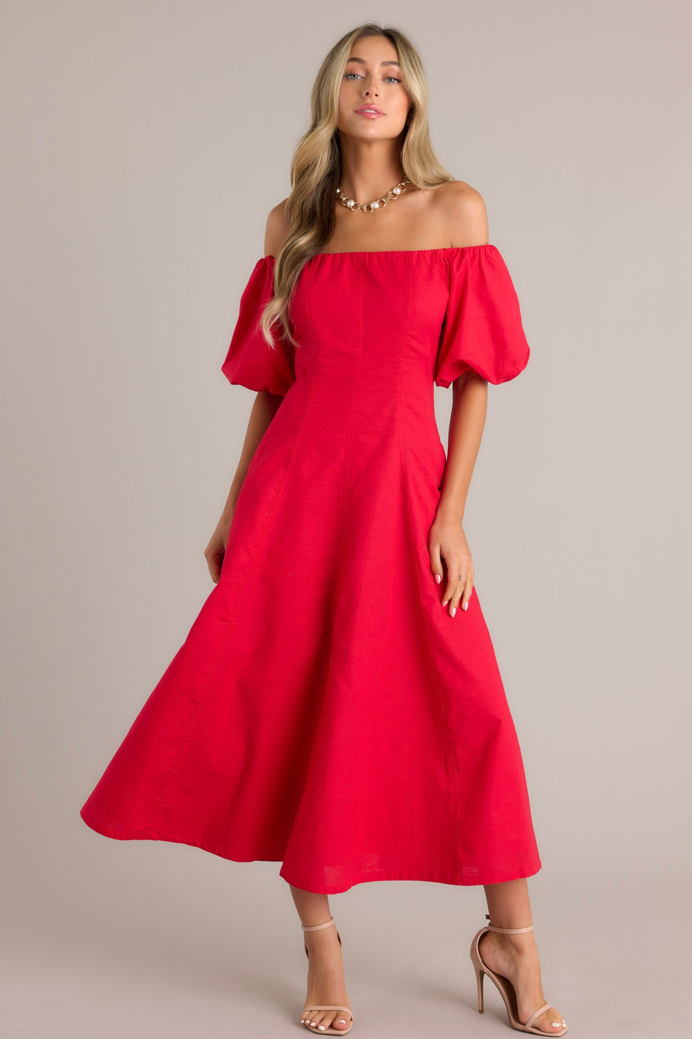 Front view of a stylish off-the-shoulder red dress with voluminous puffed sleeves, a fitted bodice, and a flowing ankle-length skirt, showcasing a fashionable and elegant design.