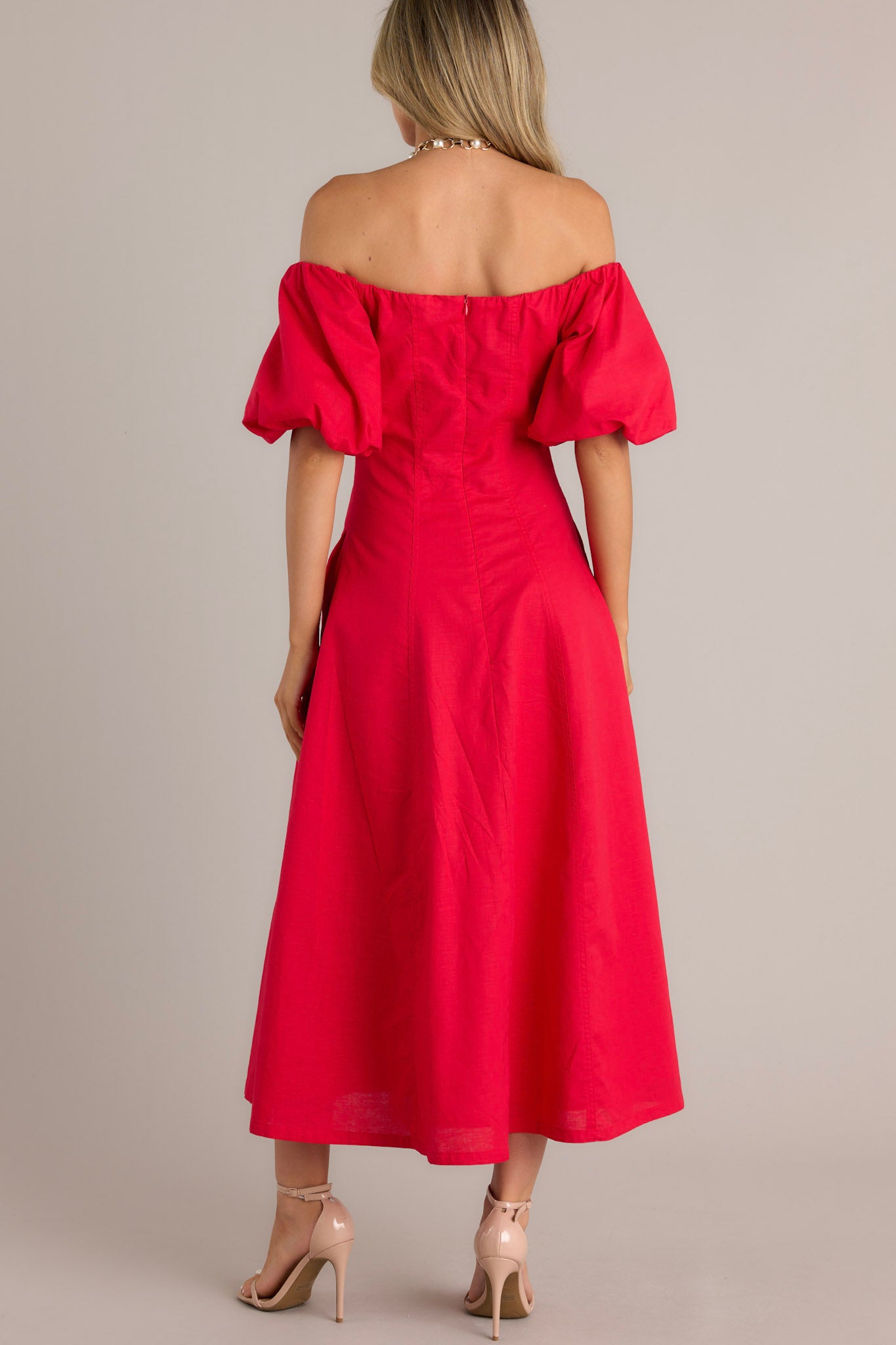 Back view of an elegant off-the-shoulder red dress with dramatic puffed sleeves, a fitted bodice, and a flowing ankle-length skirt.
