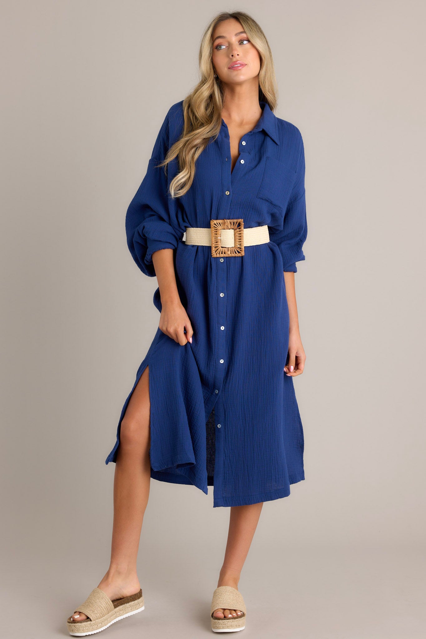 Full body view of this Navy Gauze Midi Dress featuring a collared neckline, functional buttons down the front, a front pocket on the left side of the bust, long sleeves with a cuff secured by a functional button, and two slits up the bottom hemline ending just below the knee.