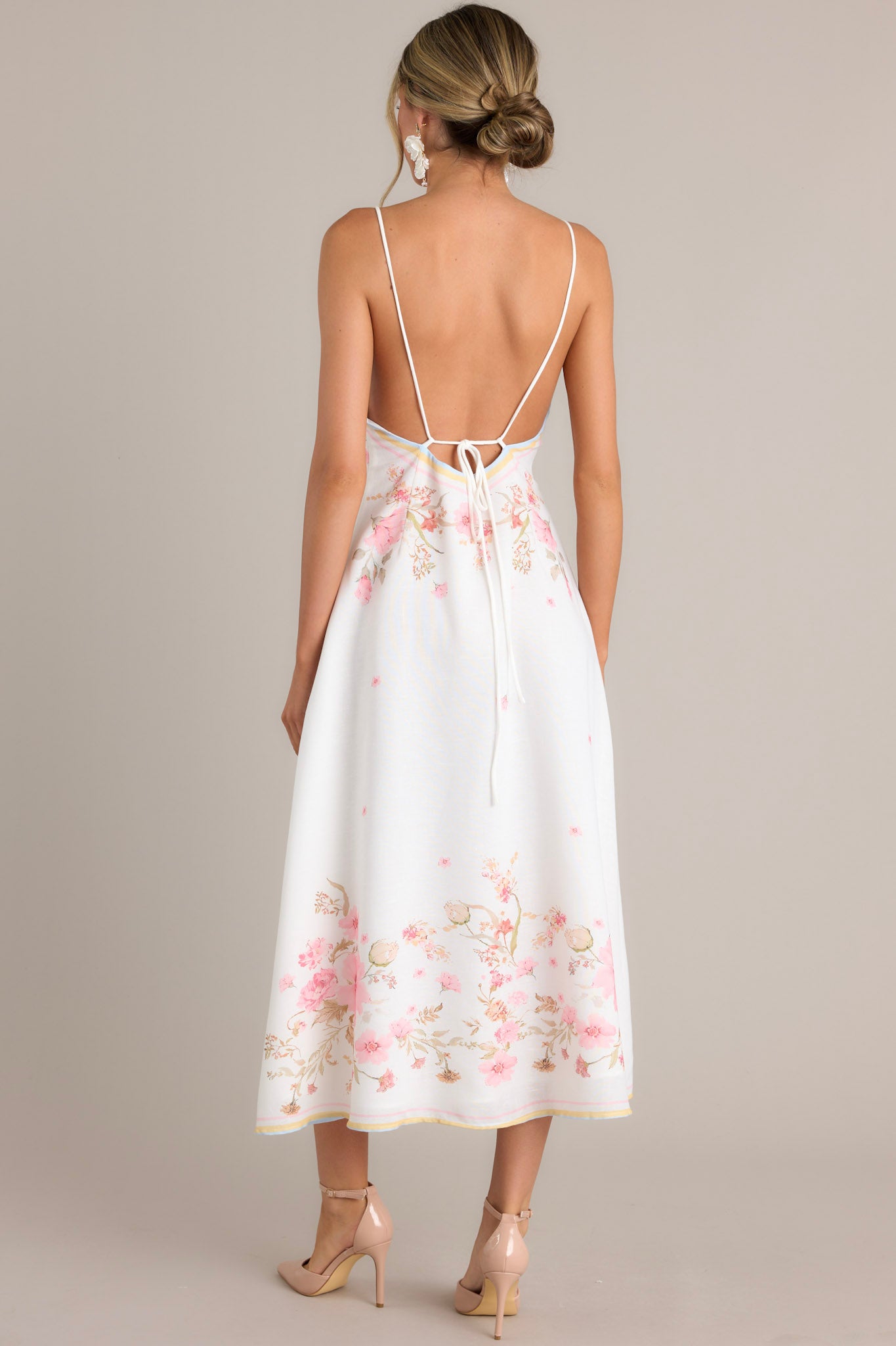 Back view of this floral midi dress that features a v-neckline, thin adjustable self-tie straps, an open back, a discrete side zipper, a delicate floral pattern, and a front slit.