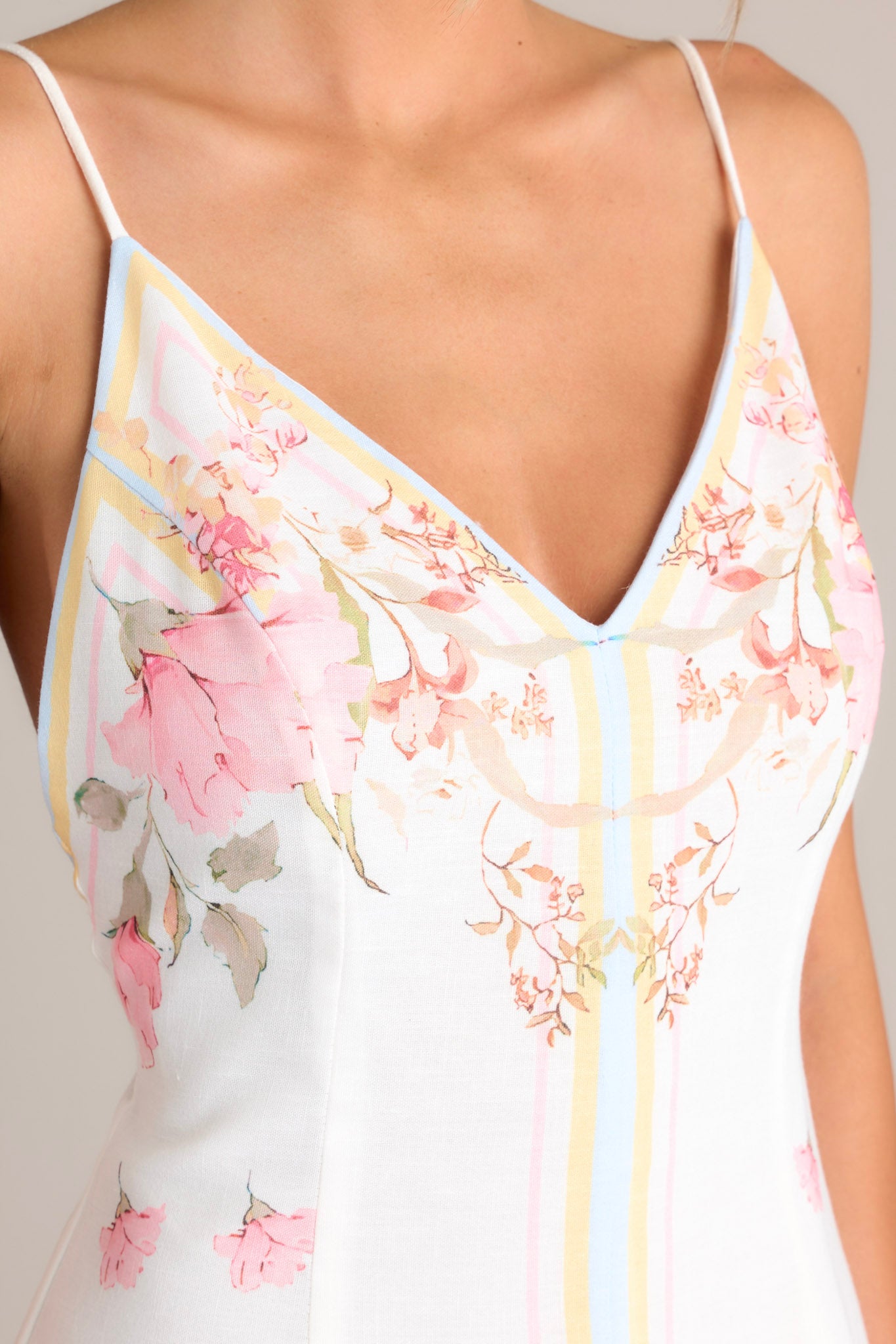 Close up view of this floral midi dress that features a v-neckline, thin adjustable self-tie straps, an open back, a discrete side zipper, a delicate floral pattern, and a front slit.