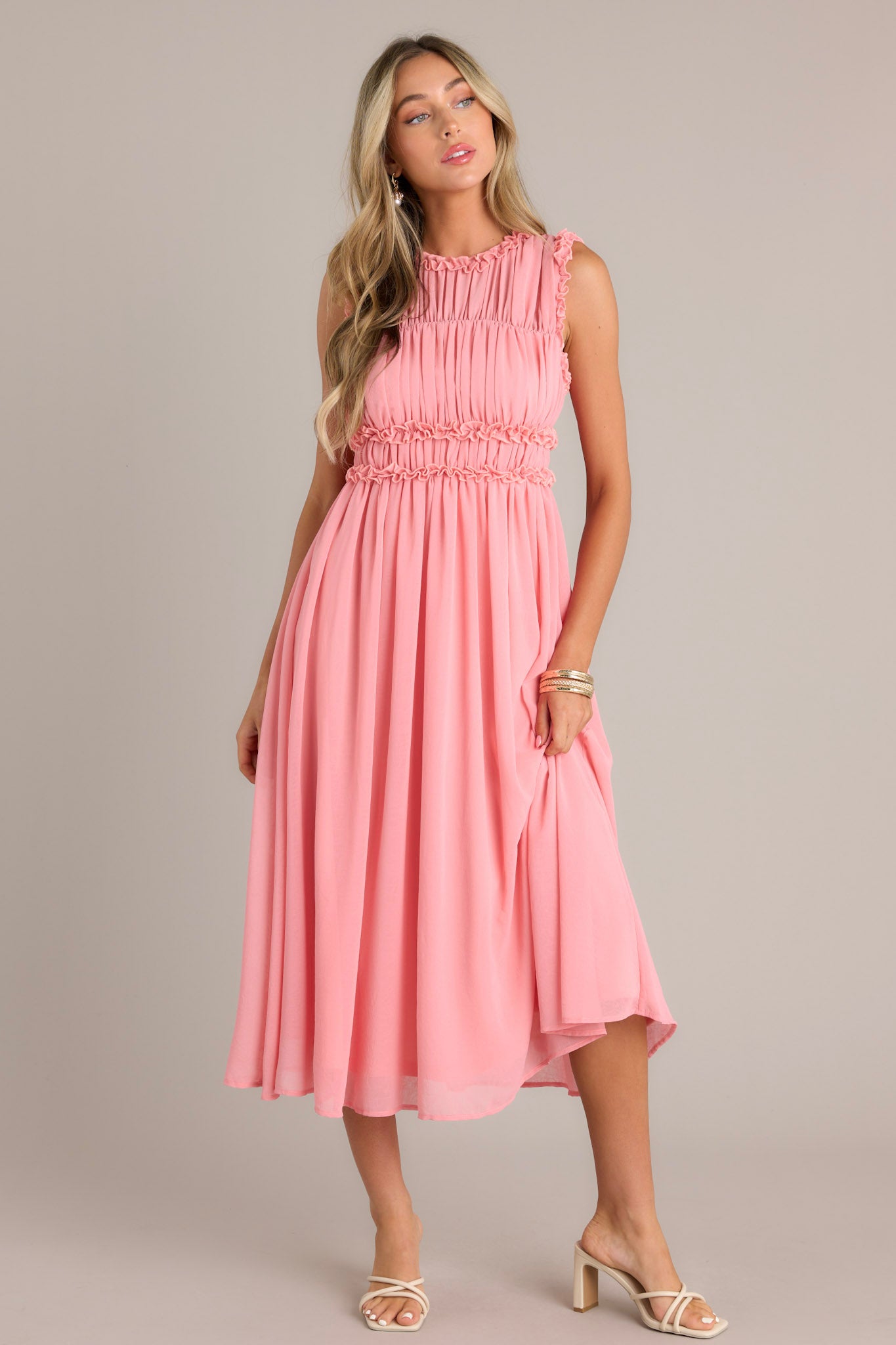 Pink coral dress with a high neckline, accented with ruffles across the bust, a back zipper, and a keyhole opening in the back.