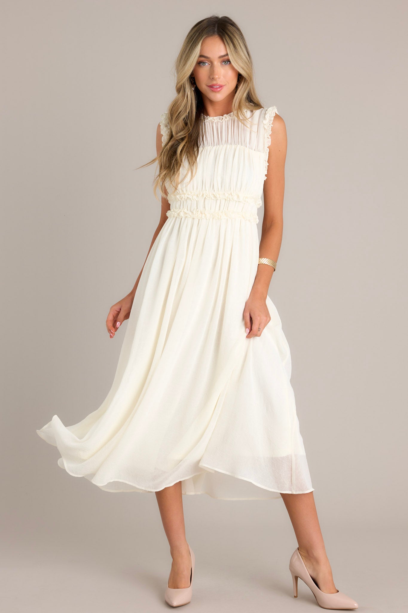 This ivory dress features a high neckline, ruffle detailing across the bust, a back zipper, and a keyhole opening at the back.