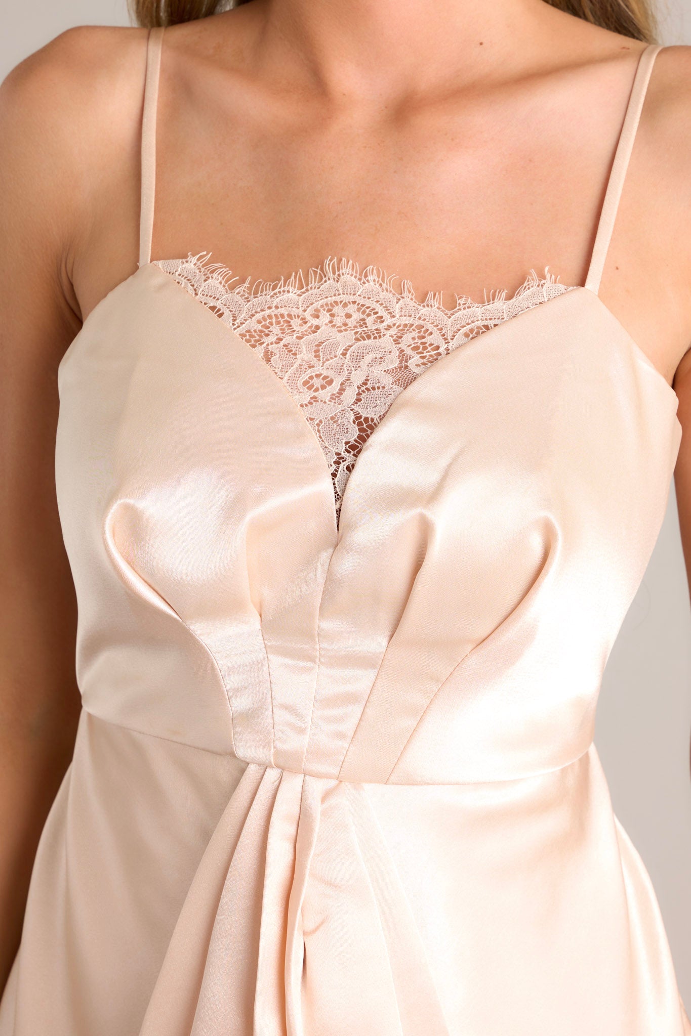 Close up view of this dress that features a sweetheart neckline with lace detailing and a pleated satin-like bodice with a lace section.