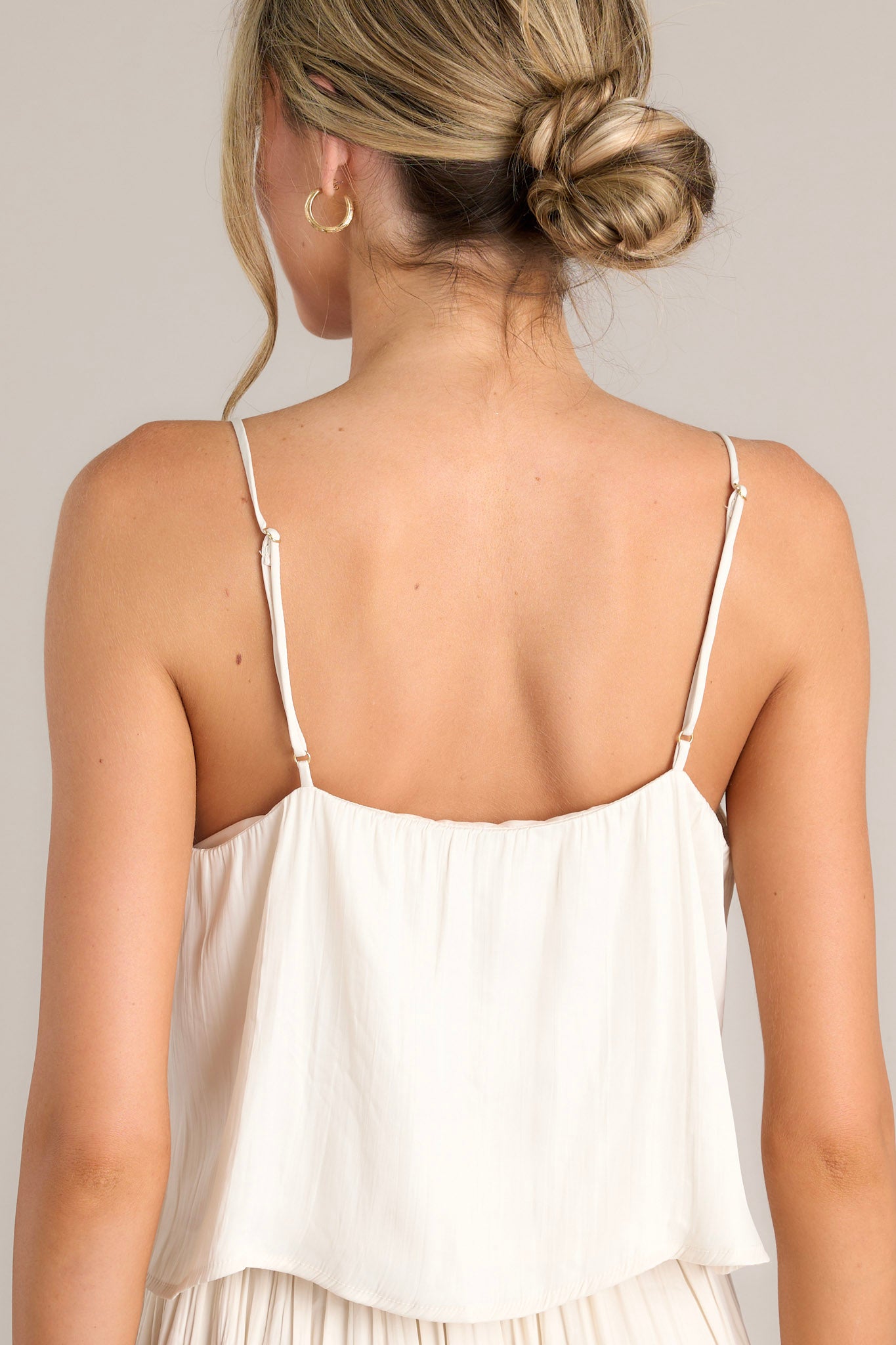 Back view of this sandstone tank that features a v-neckline, thin adjustable straps, a slightly textured material, and a cropped hemline.