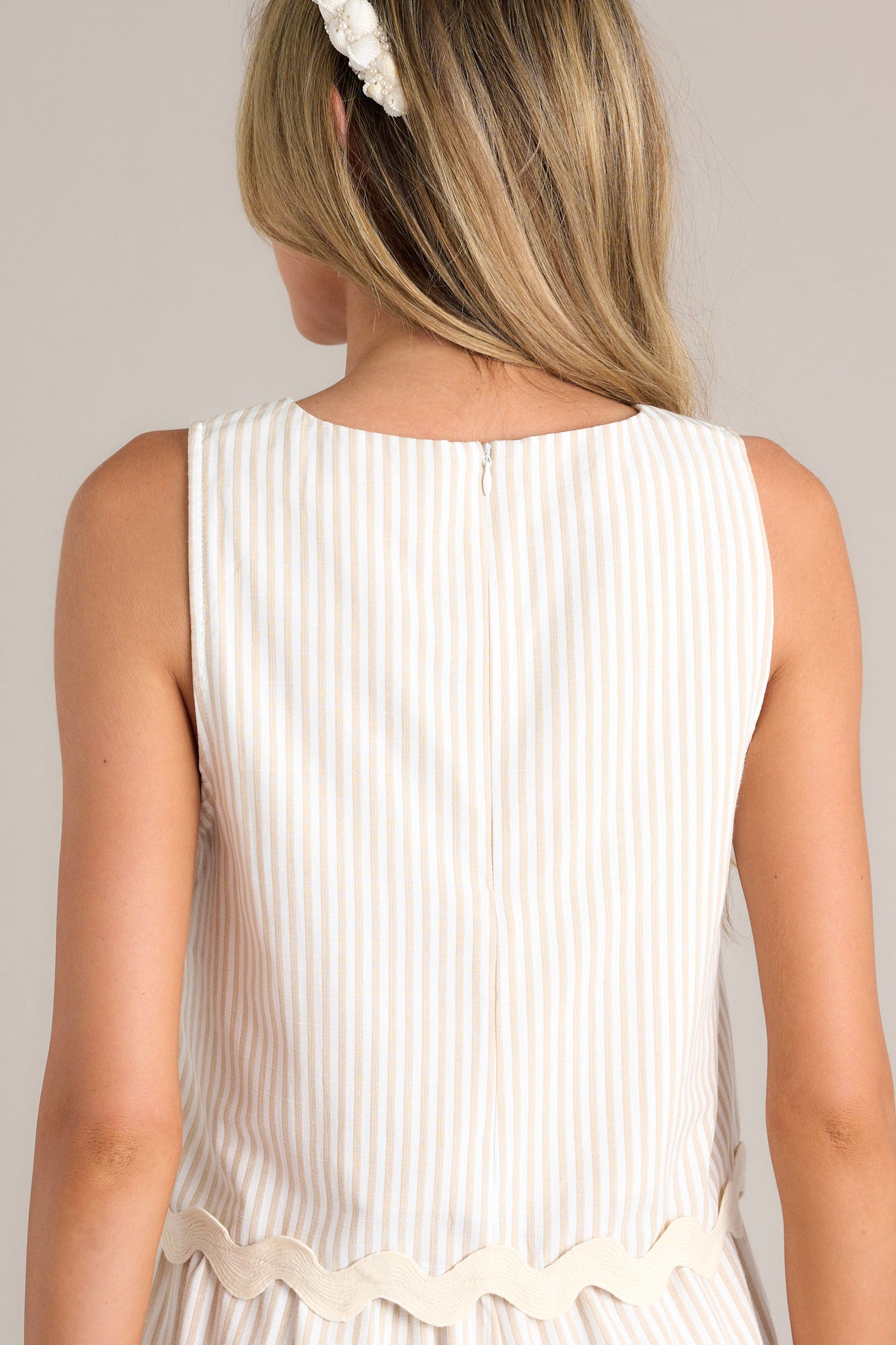 Back view of this taupe stripe tank that features a crew neckline, a wide sleeve, a discrete zipper down the back, and a ricrac hemline.