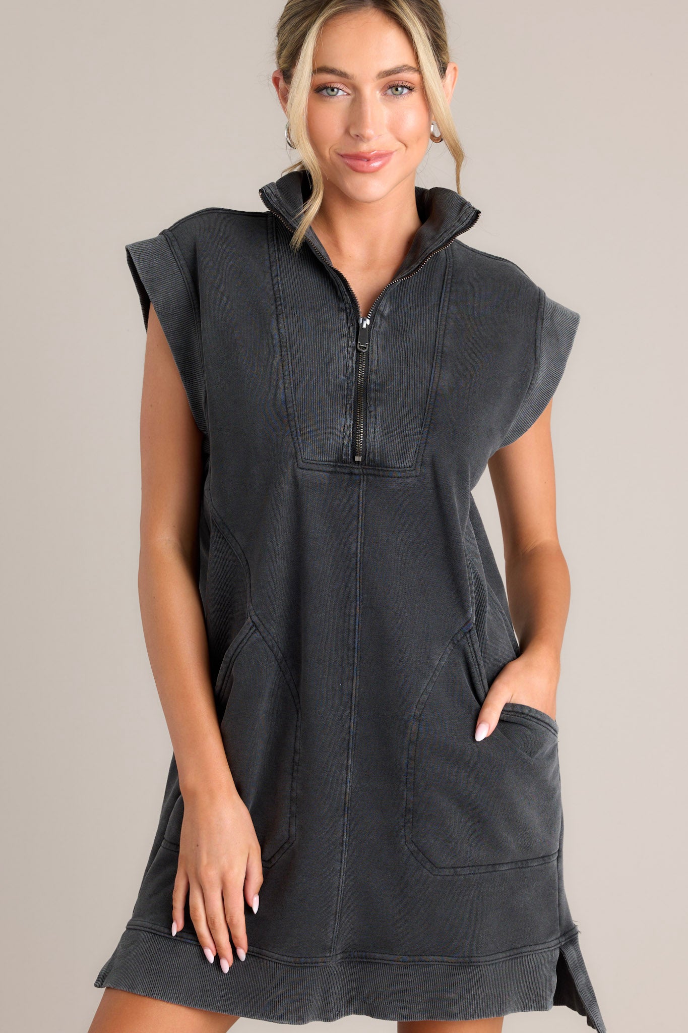 Front view of a charcoal mini dress featuring a collared v-neckline, a functional zipper front, ribbed detailing, functional front pockets, a split hemline, and wide ribbed sleeves.