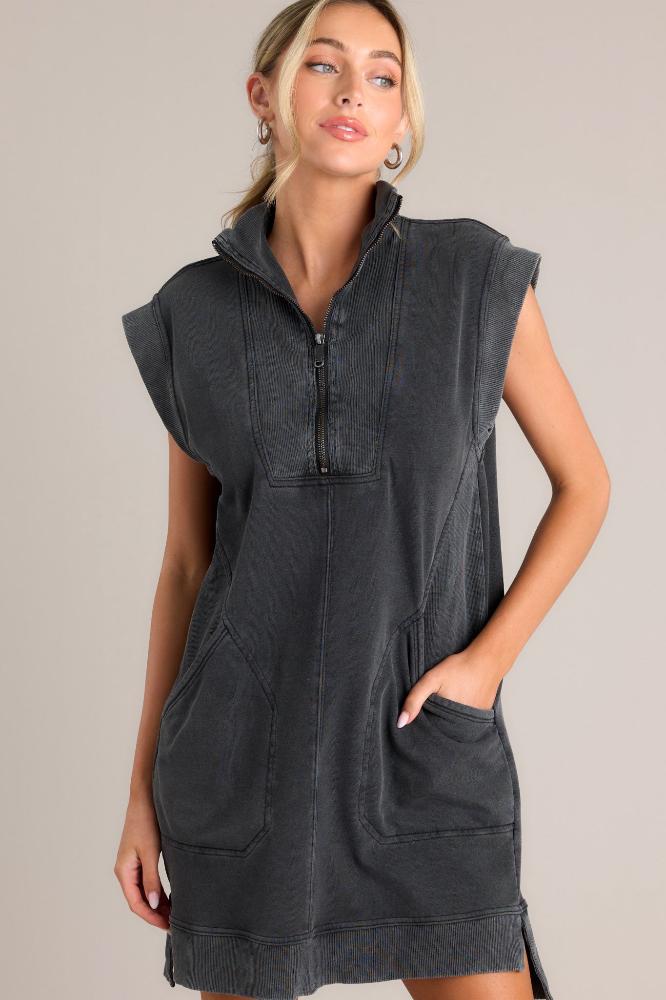 Front angled view of a charcoal mini dress featuring a collared v-neckline, functional zipper front, ribbed detailing, functional front pockets, a split hemline, and wide ribbed sleeves