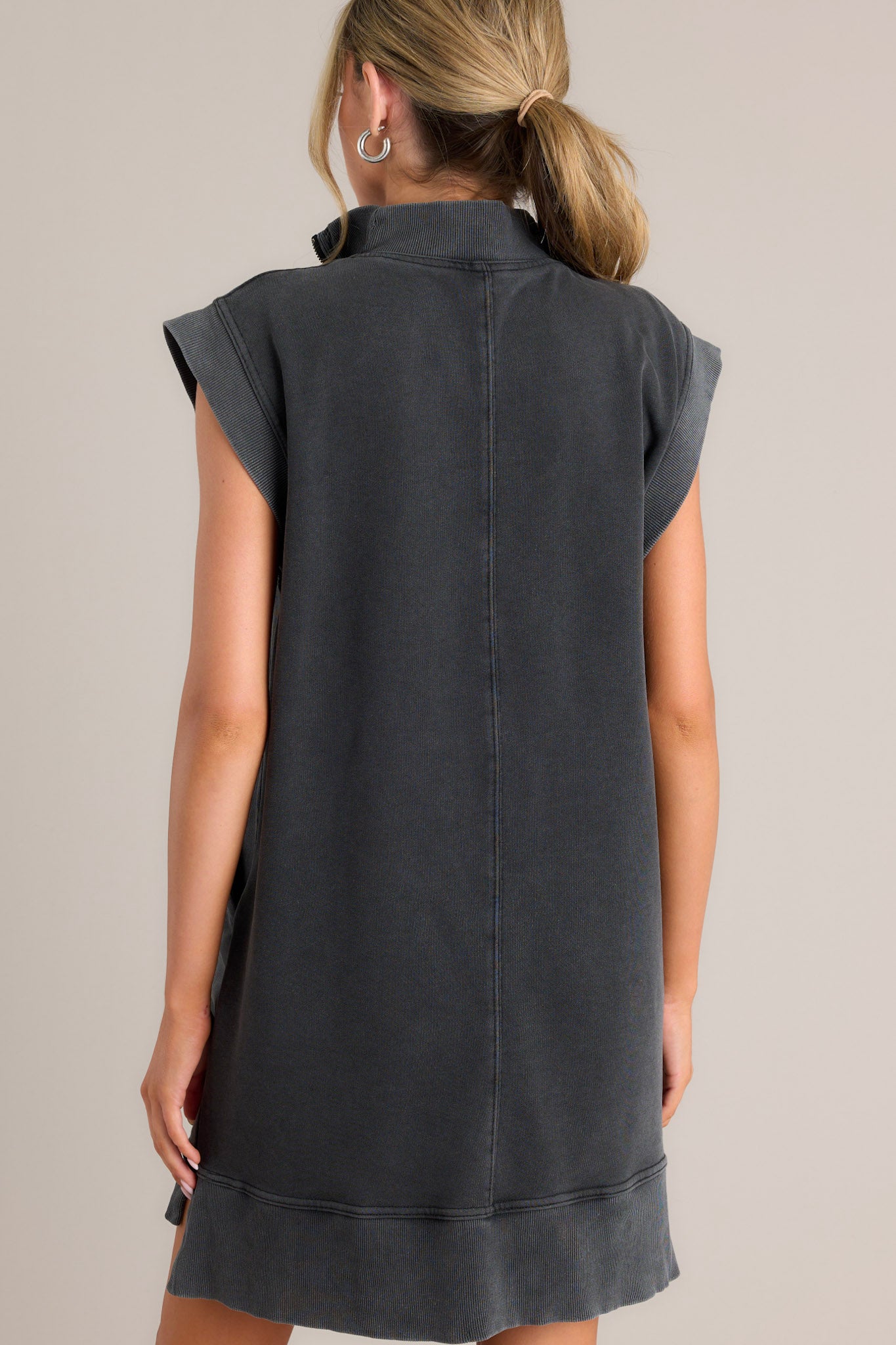 Back view of a charcoal mini dress highlighting the ribbed detailing, the cut and shape of the dress, and the wide ribbed sleeves.
