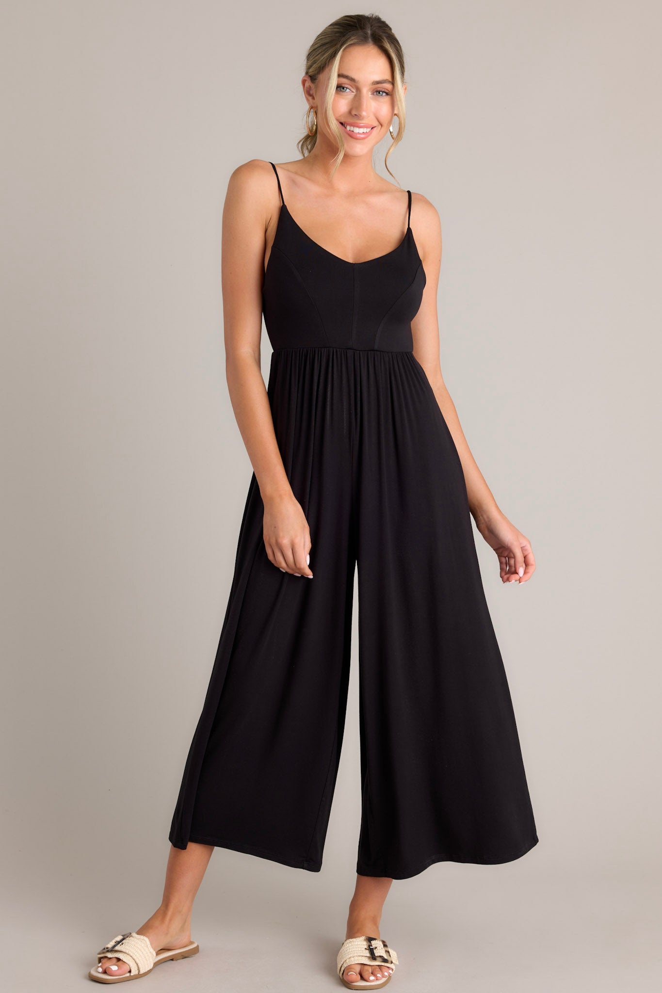 Front view of this black jumpsuit showcasing the movement in the wide legs. 