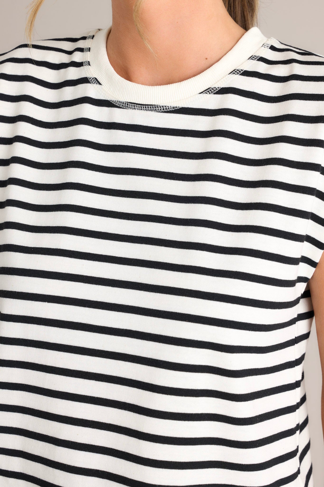 Detailed view on the fabric of this white stripe top that features a crew neckline, short cap sleeves, and a classic stripe pattern.